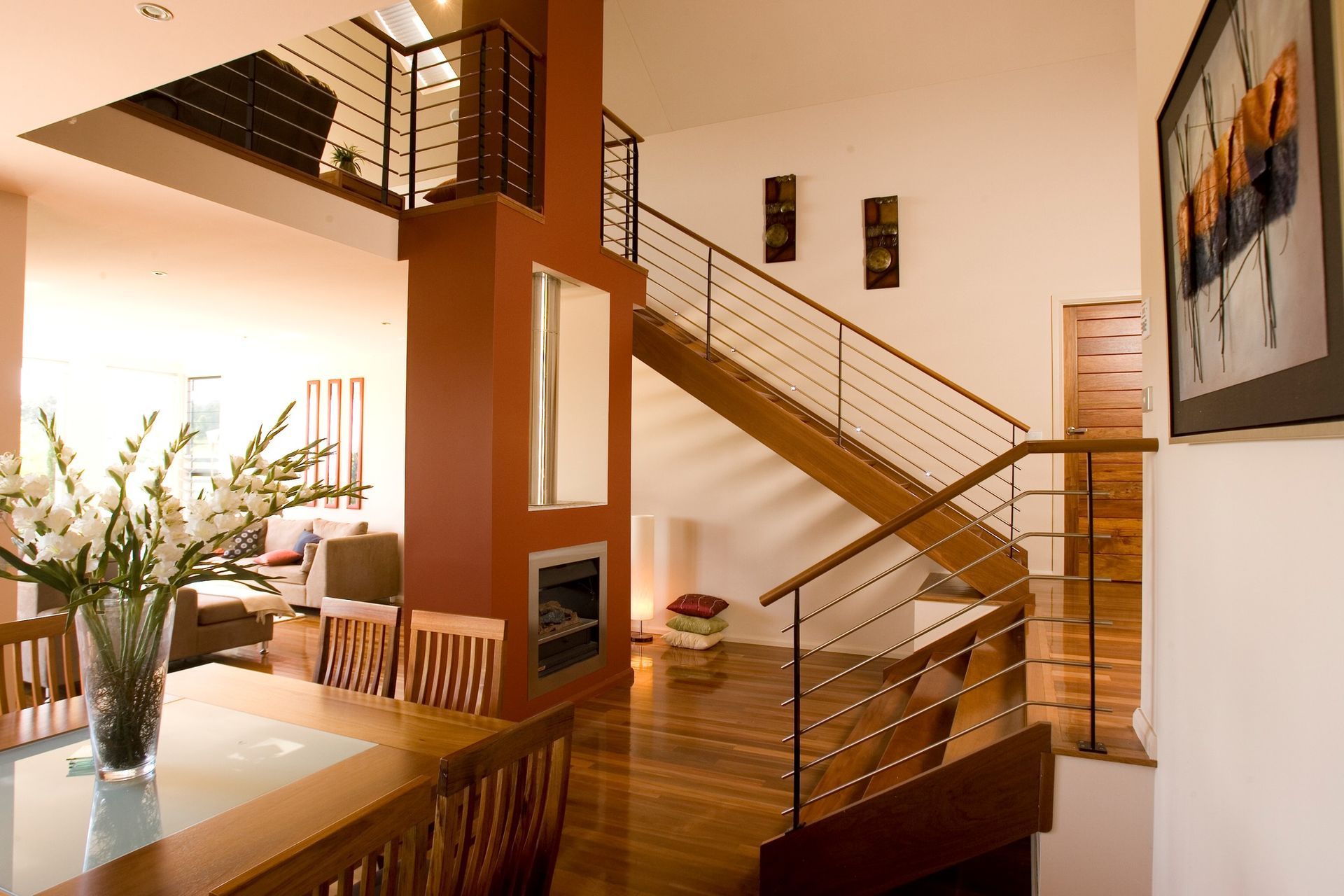 Wooden staircase in a modern home with red accent wall, and dining table.