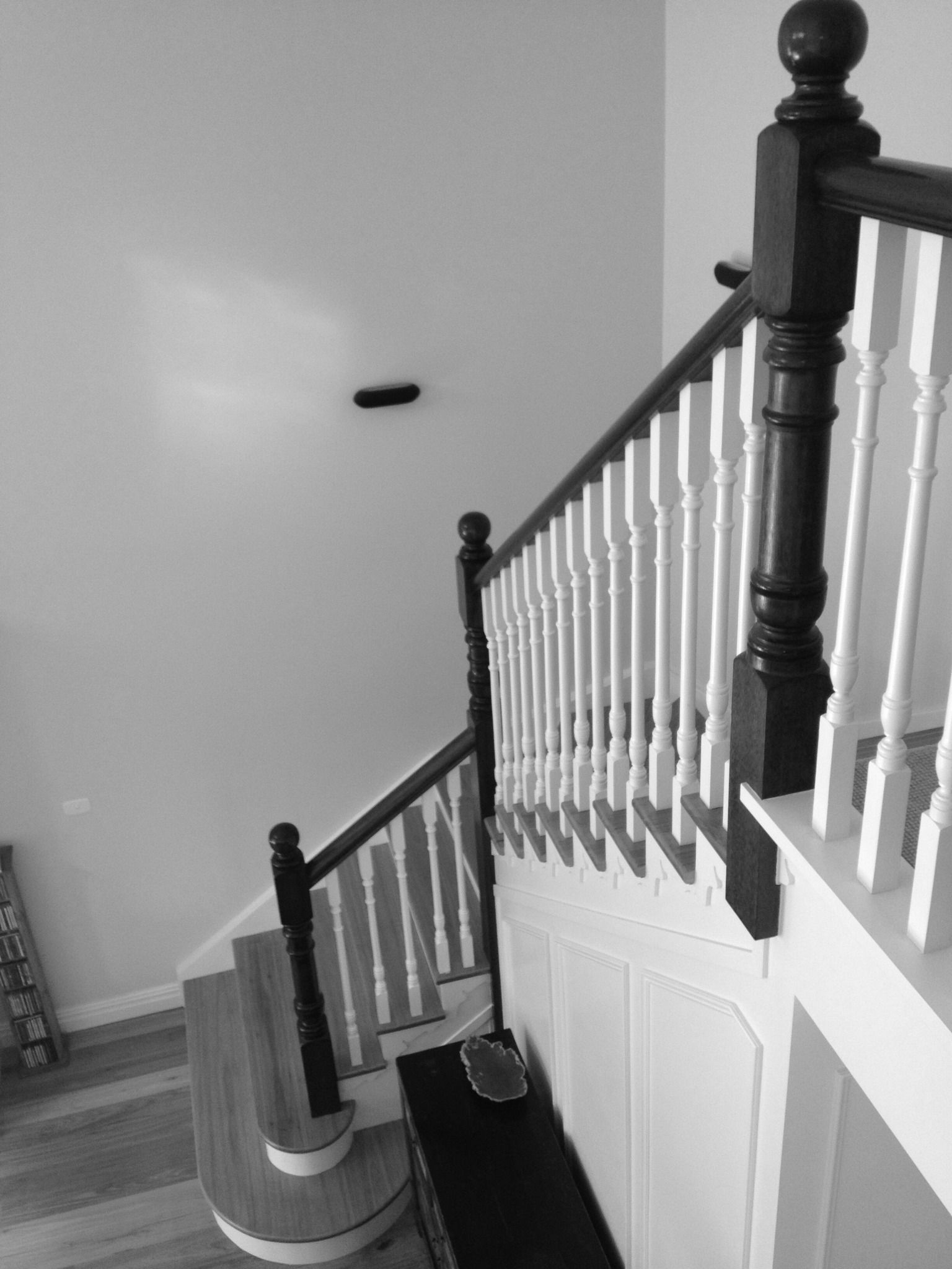 Black and white photo of a staircase. Staircase has white spindles and dark wood handrails and posts.