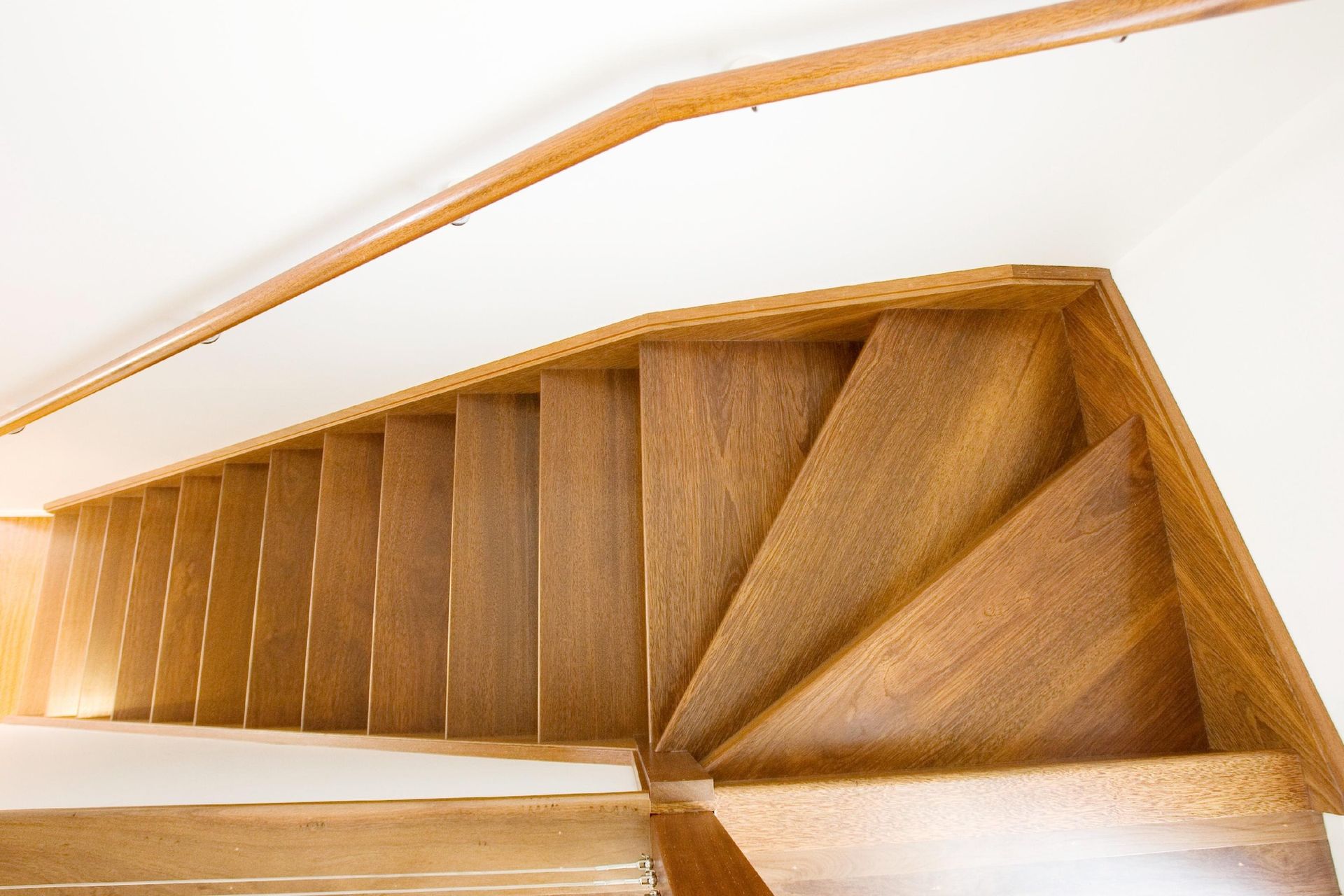 Wooden staircase with a curved corner, viewed from above.