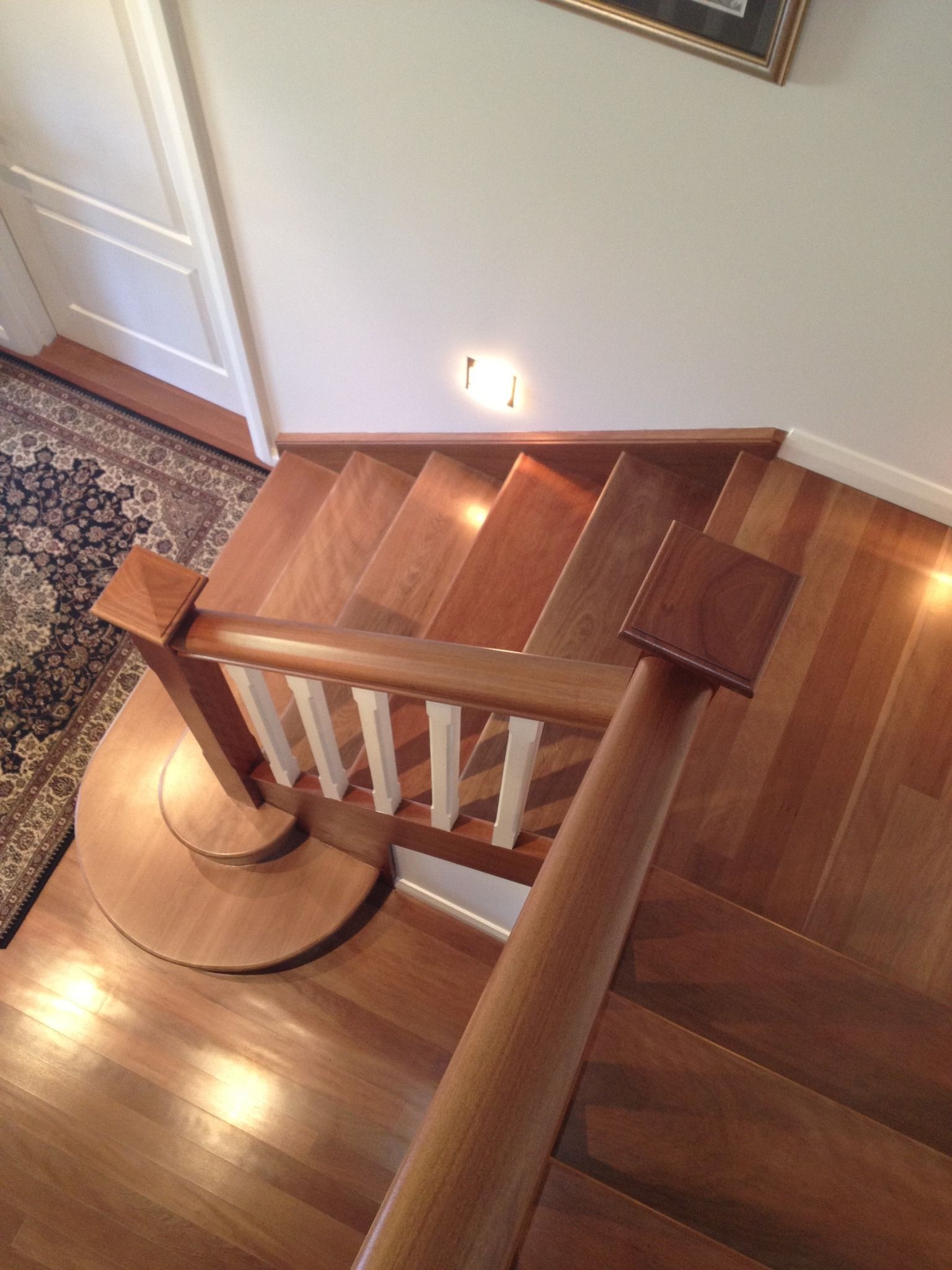 Wooden staircase with handrails and a light fixture, viewed from above.