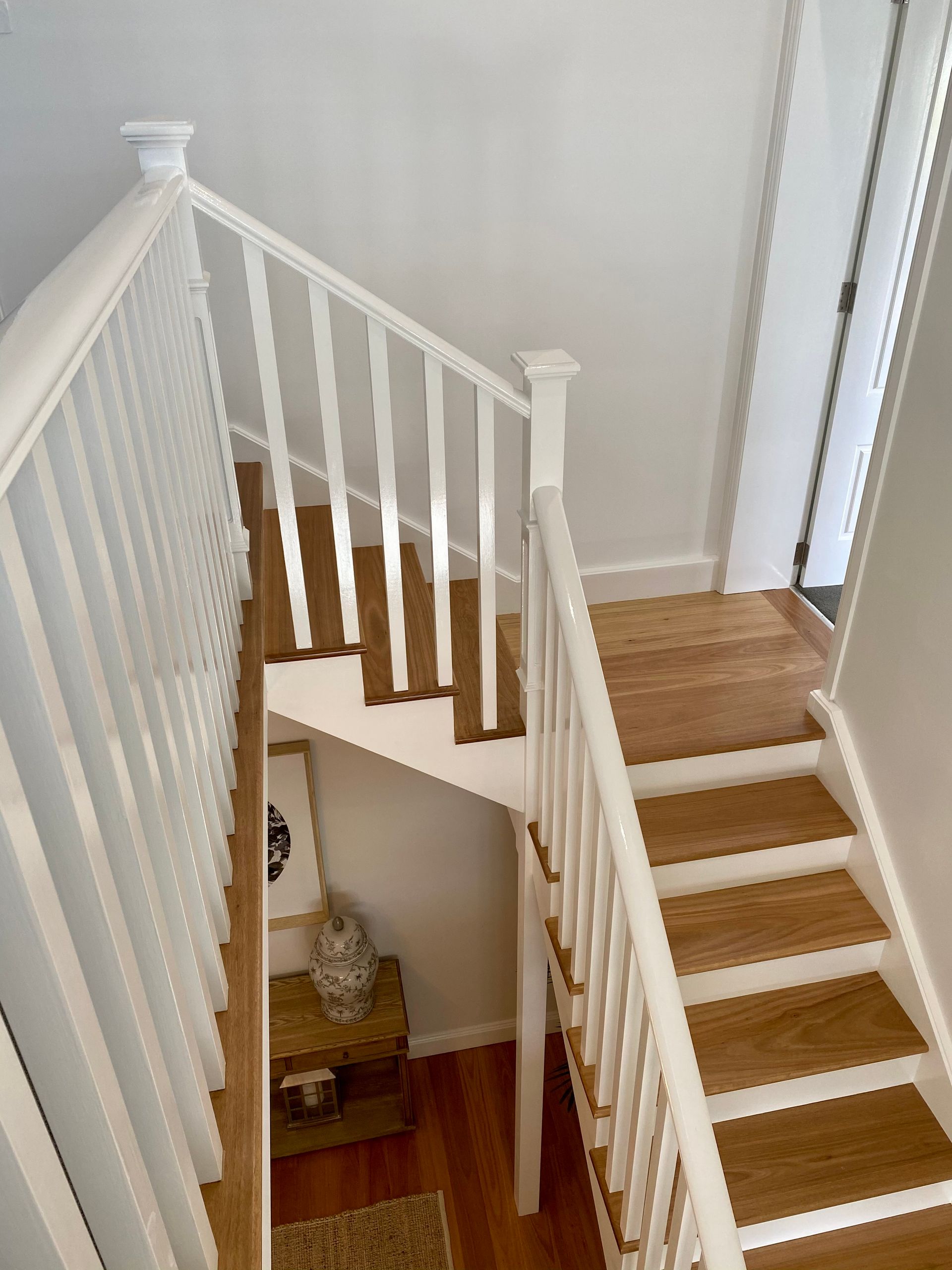 White staircase with wooden steps and railing in a home.