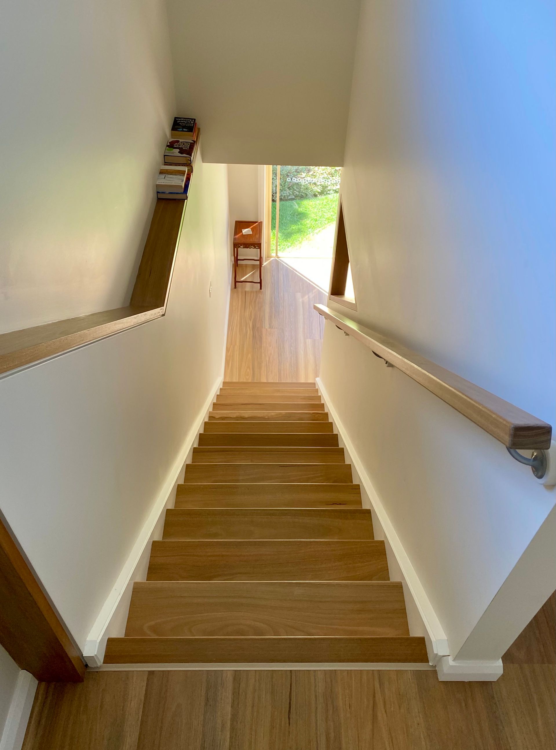 Spacious foyer with wooden floor and staircase, leading to a second-floor landing. A chandelier hangs above.