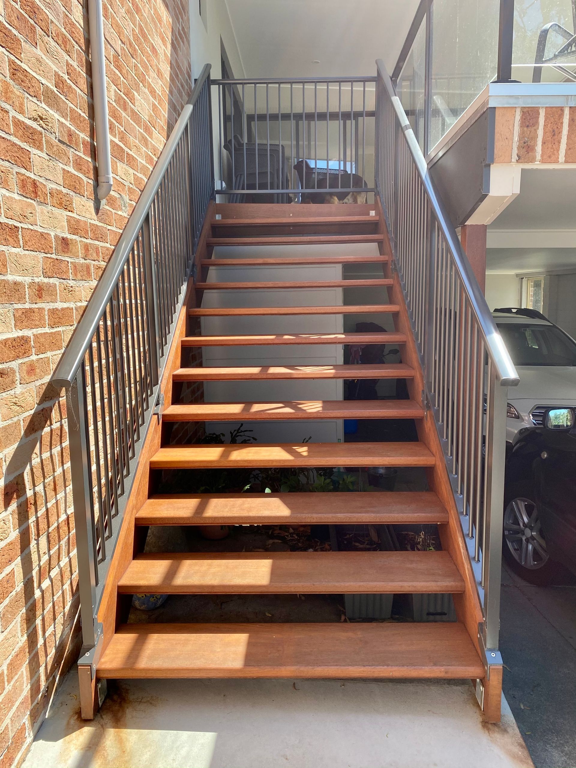 Wooden outdoor stairs with metal railing, leading up to a higher level.