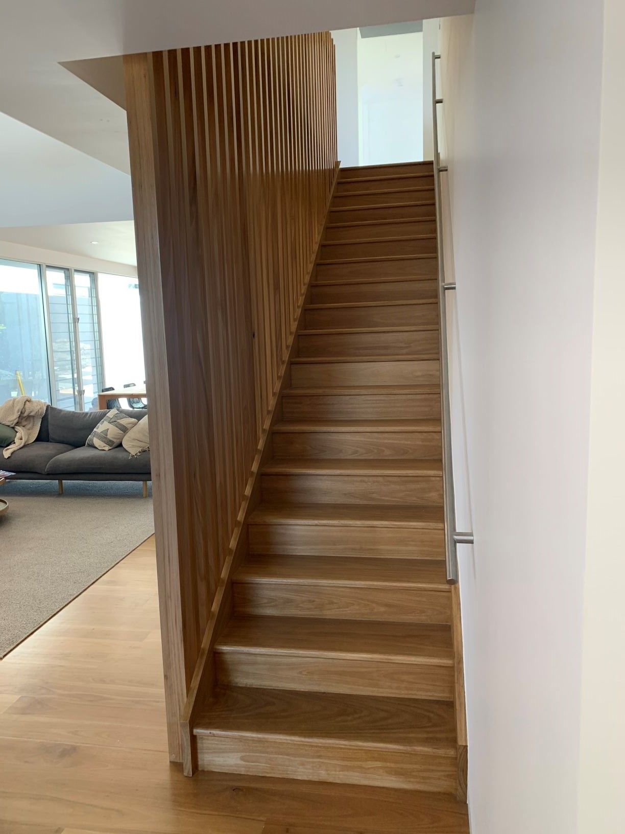 Wooden outdoor staircase with black railing leading up to a deck.