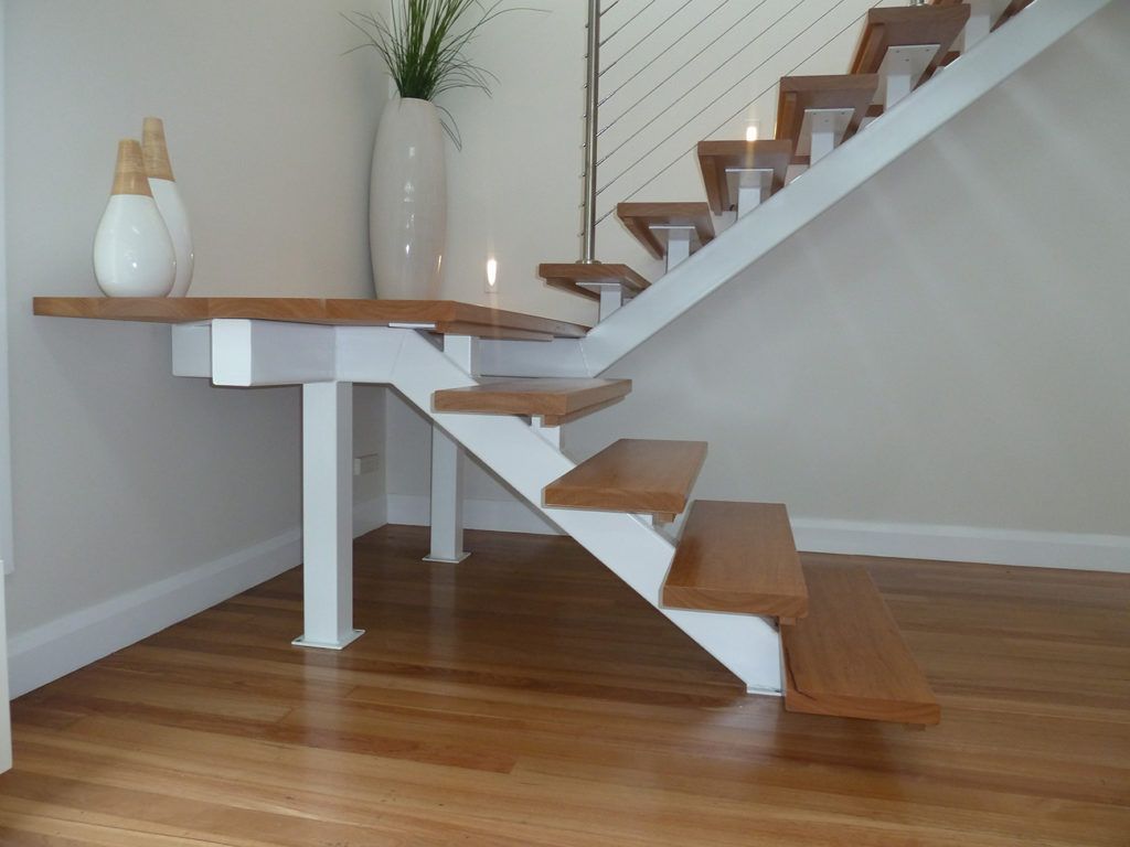 Wooden staircase going upwards with a dark brown handrail and tan walls.