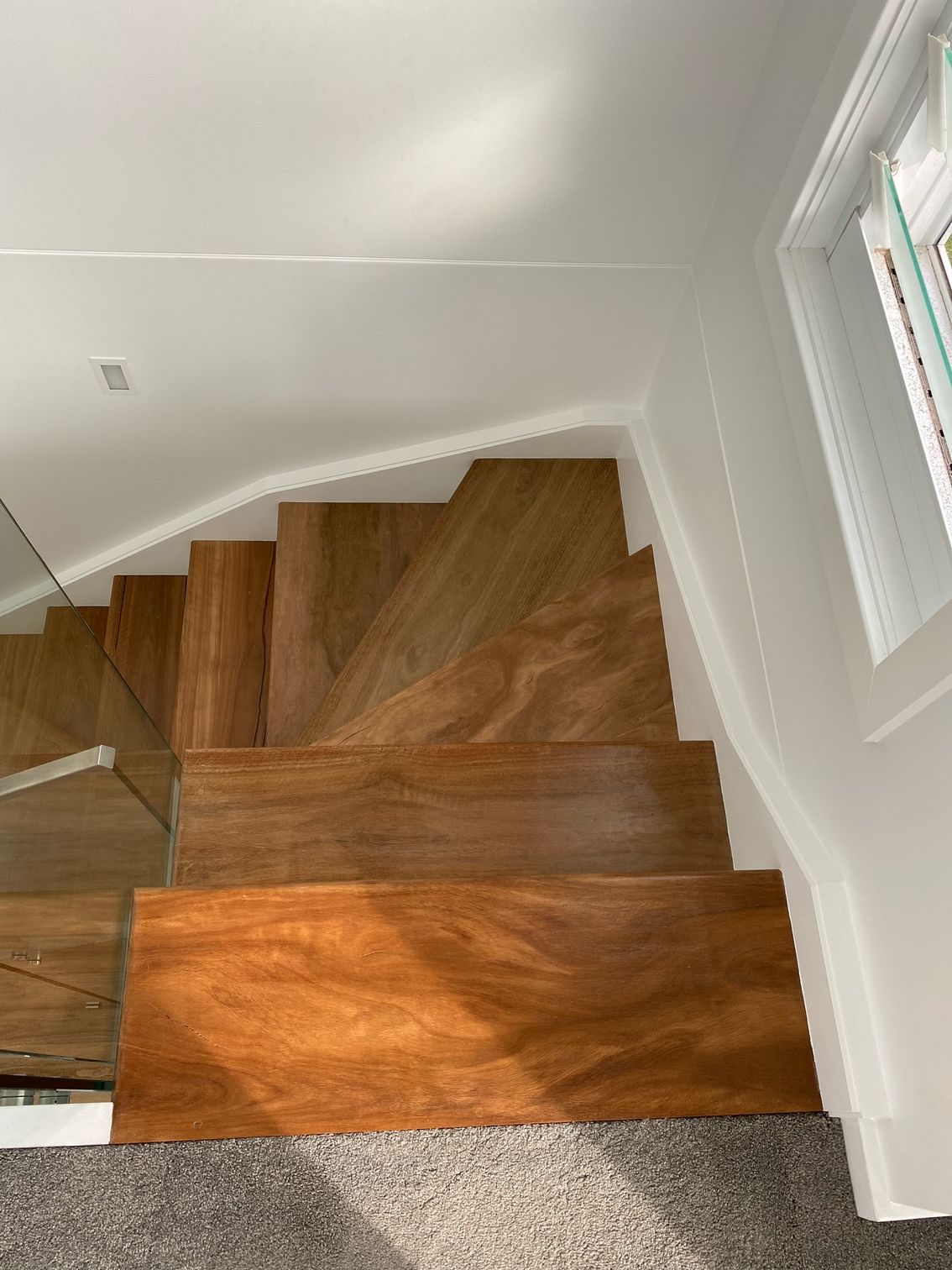 White stairs ascend past a metal and glass railing; beige building in the background.