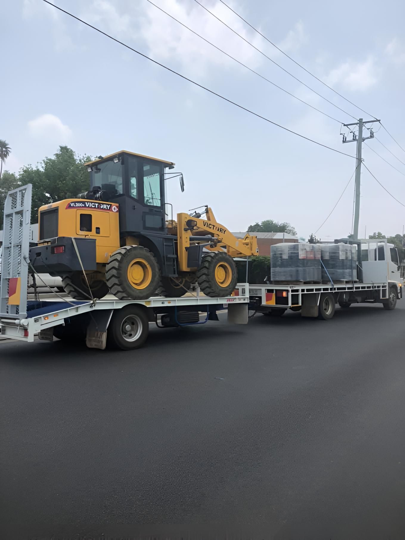 A Yellow Tractor is Sitting on Top of a Flatbed Truck — MacCallum & Company In Scone, NSW