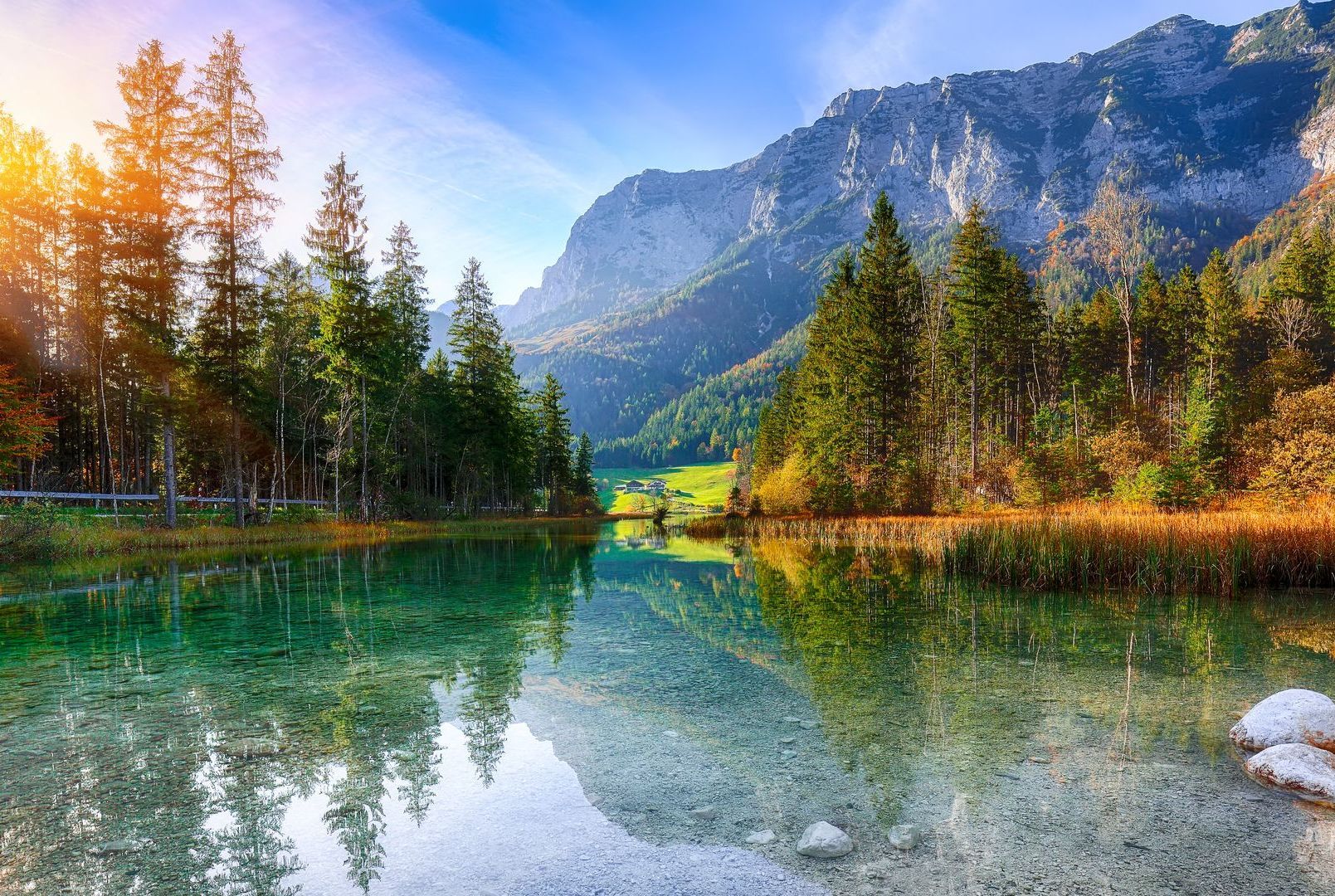 There is a lake in the middle of a forest with mountains in the background.