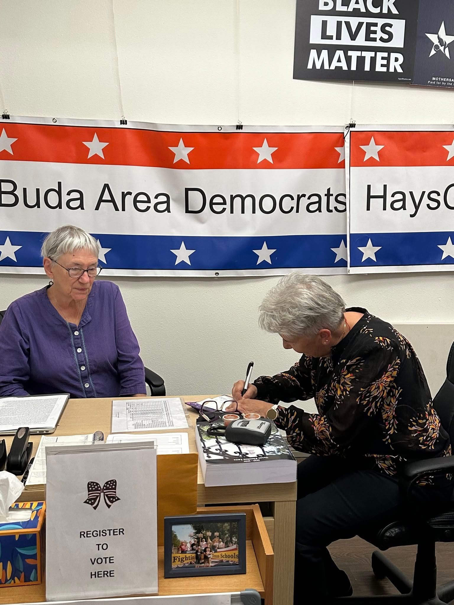 Two women at a desk in a room with a 