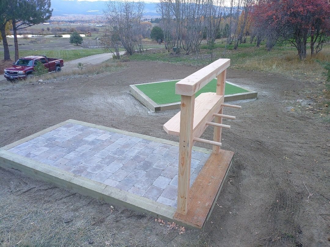 Horseshoe game setup outdoors with wooden platforms and target.