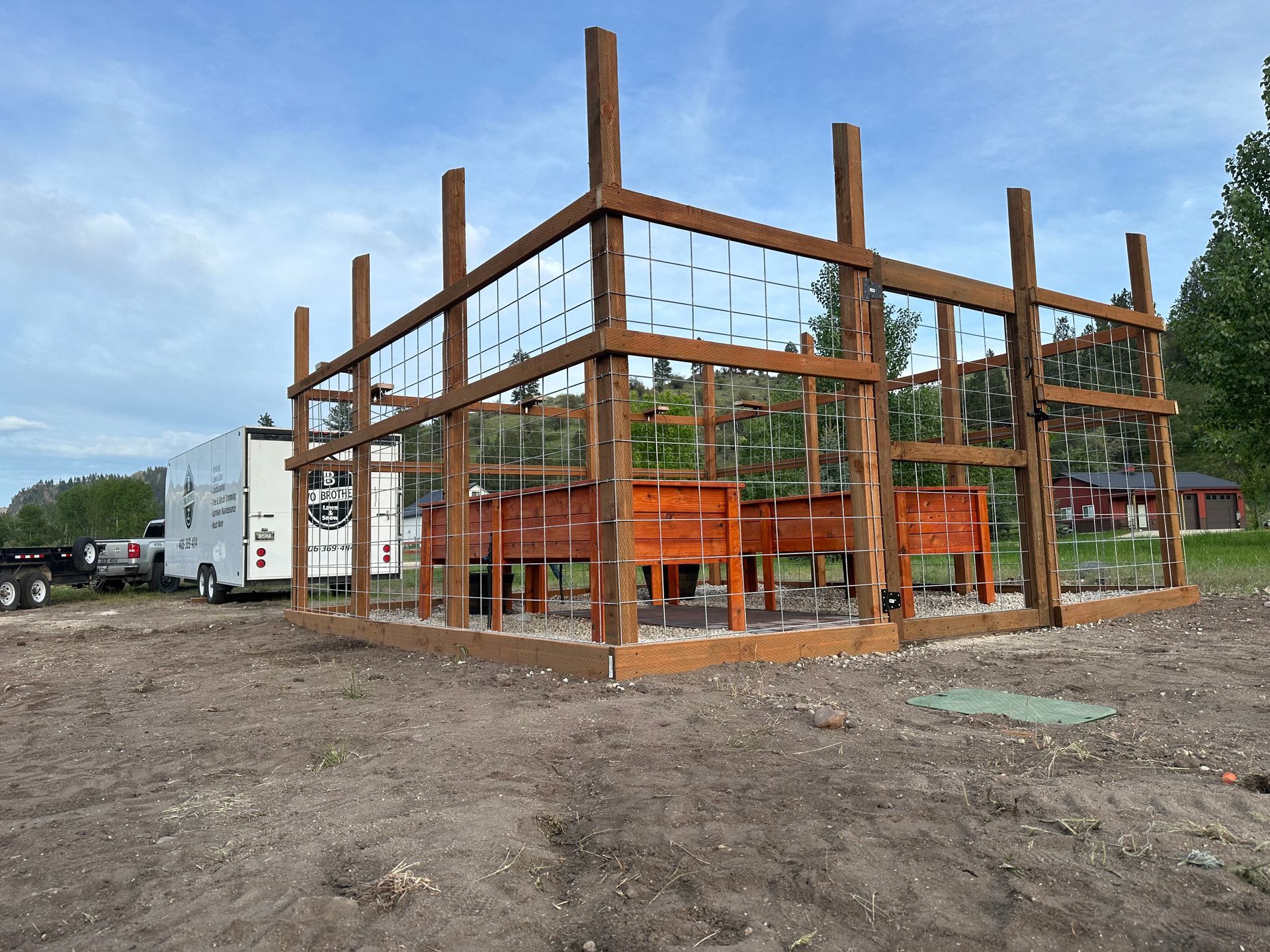 Wooden structure with planters and wire lattice; construction site with trailer.