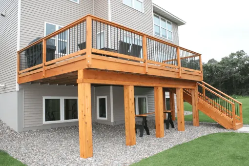 A person wearing work gloves using a clamp on deck construction outside.