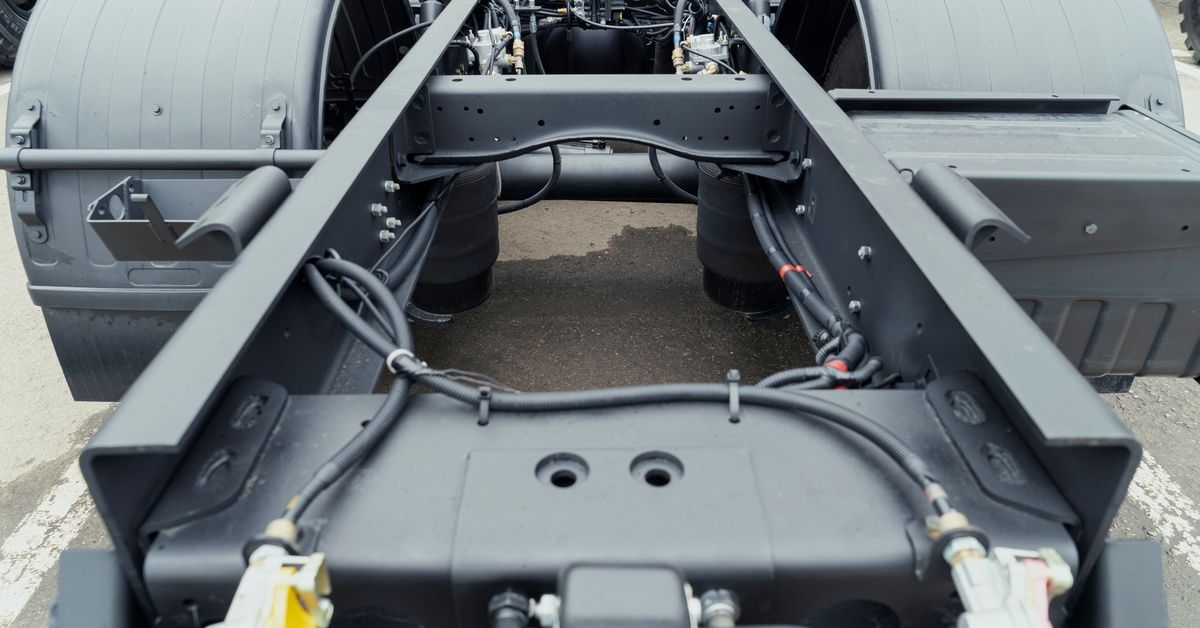 A clean, black, trailer truck frame that looks brand new. There is no trailer on the frame itself.
