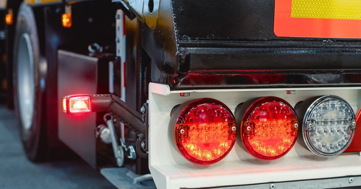 A close-up shot of a trailer's red and white brake lights. The turn signal light flashes a bright red.