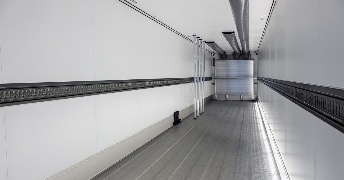 The interior of an empty semi-trailer. It is in perfect condition with a clean floor and white walls.