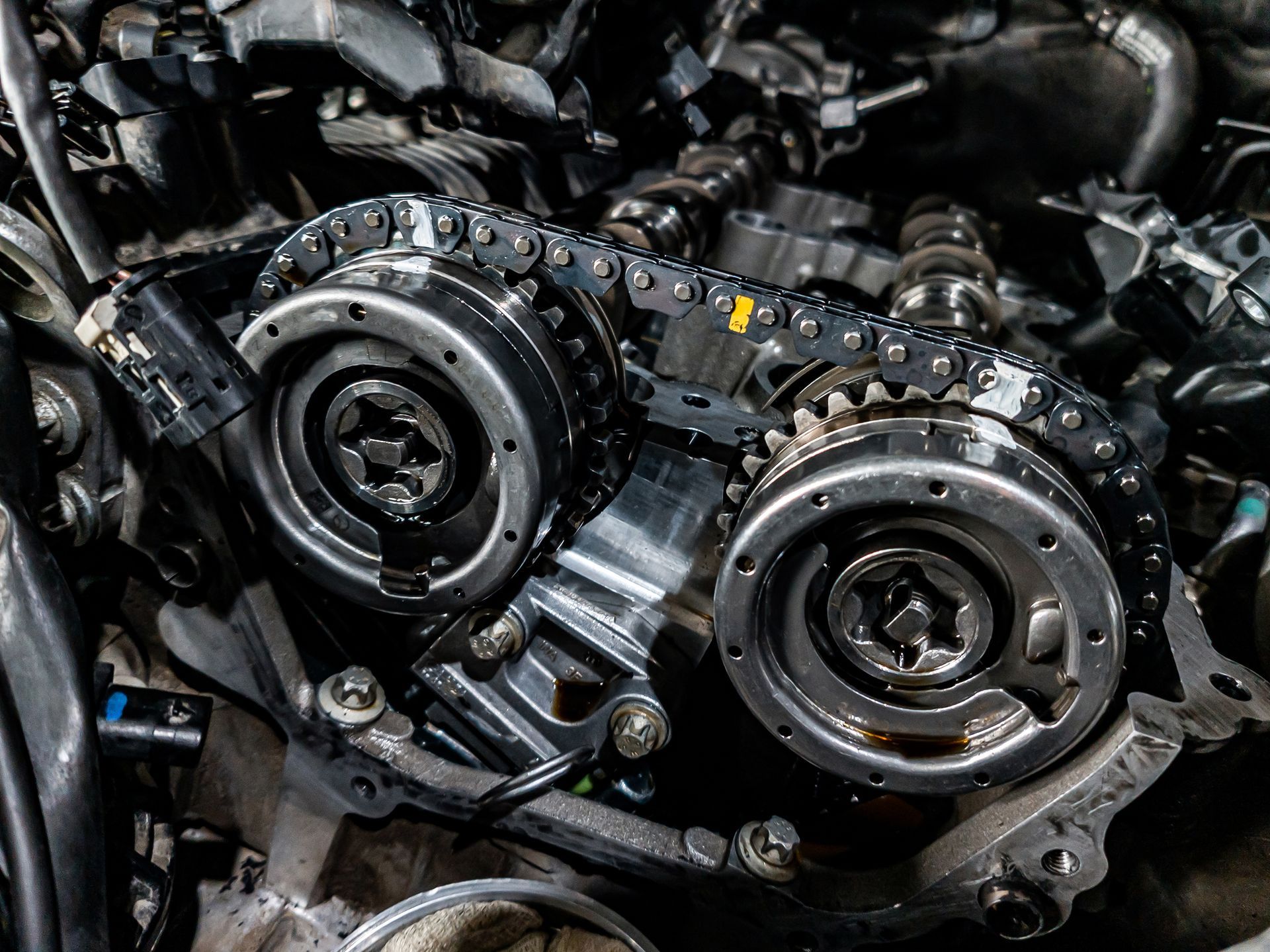 Close-up of an engine with a timing chain and gears. Metallic components are visible, likely inside a car.