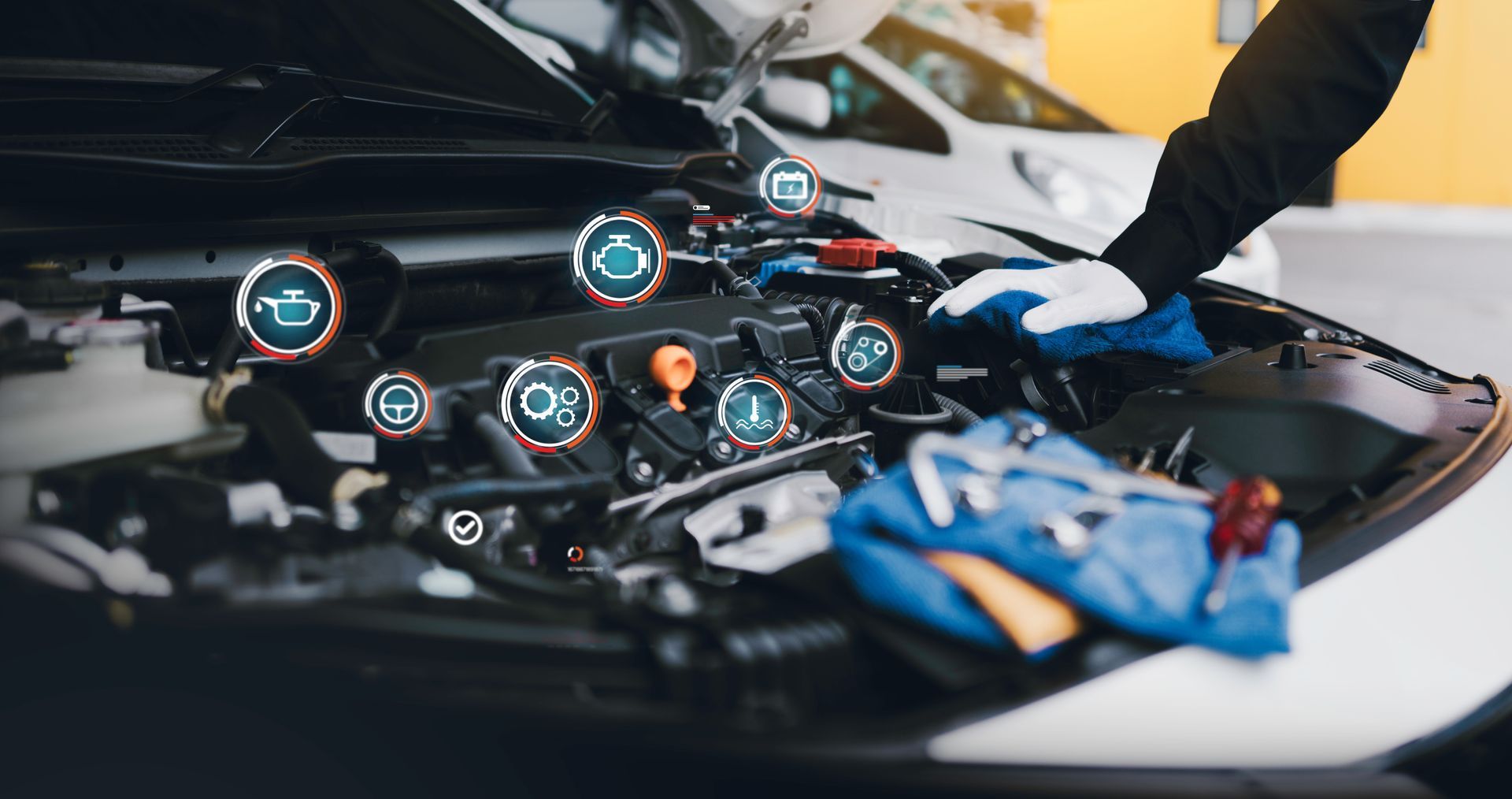 Mechanic working on car engine, tools and blue rag in foreground, overlaid with digital diagnostic icons.