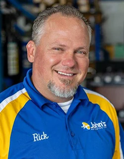 Man smiling, wearing a blue shirt with yellow accents; 