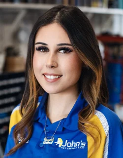 Woman in blue and yellow shirt smiling, in an auto repair shop.