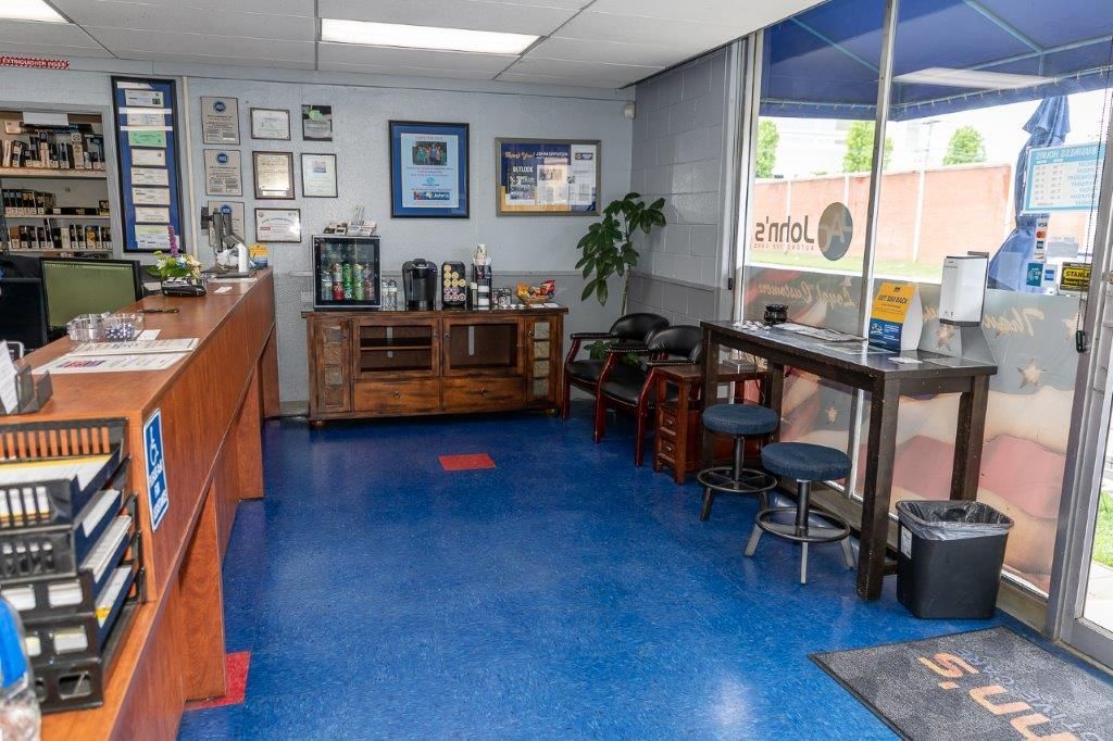 Interior of an auto repair shop; blue speckled floor, reception desk, waiting area, and awards displayed on the wall.