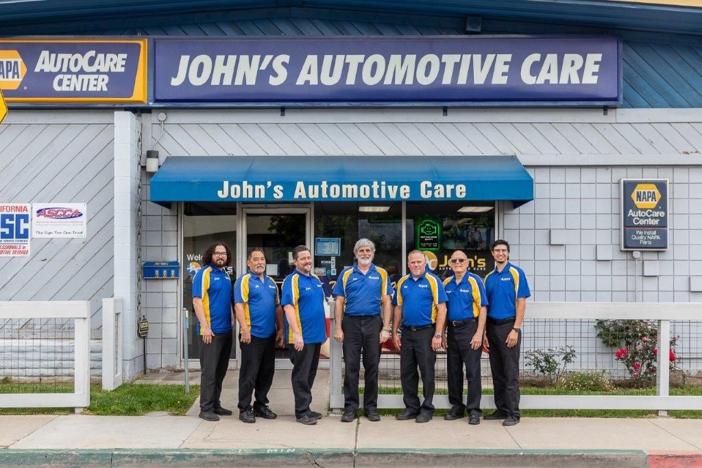 John's Automotive Care shop with a group of employees in matching blue and yellow shirts.