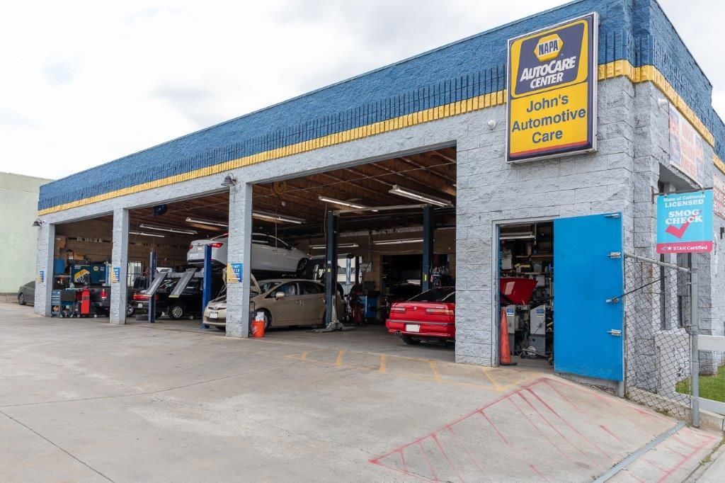 Auto repair shop with open bays, cars on lifts, and a blue door.