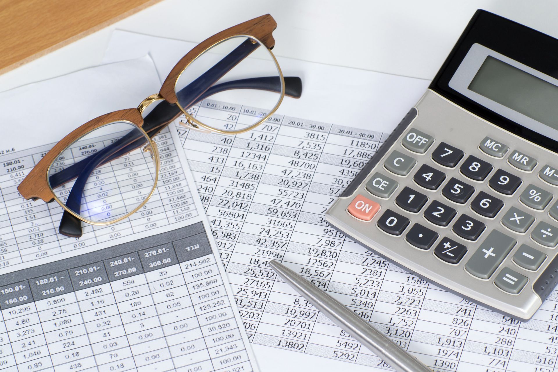 Calculator, glasses, and pen on financial documents.
