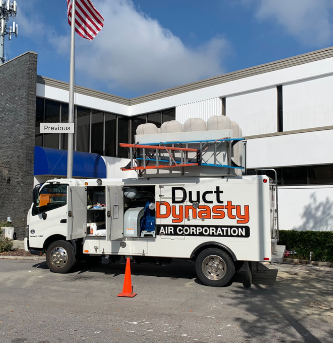 A duct dynasty truck is parked in front of a building