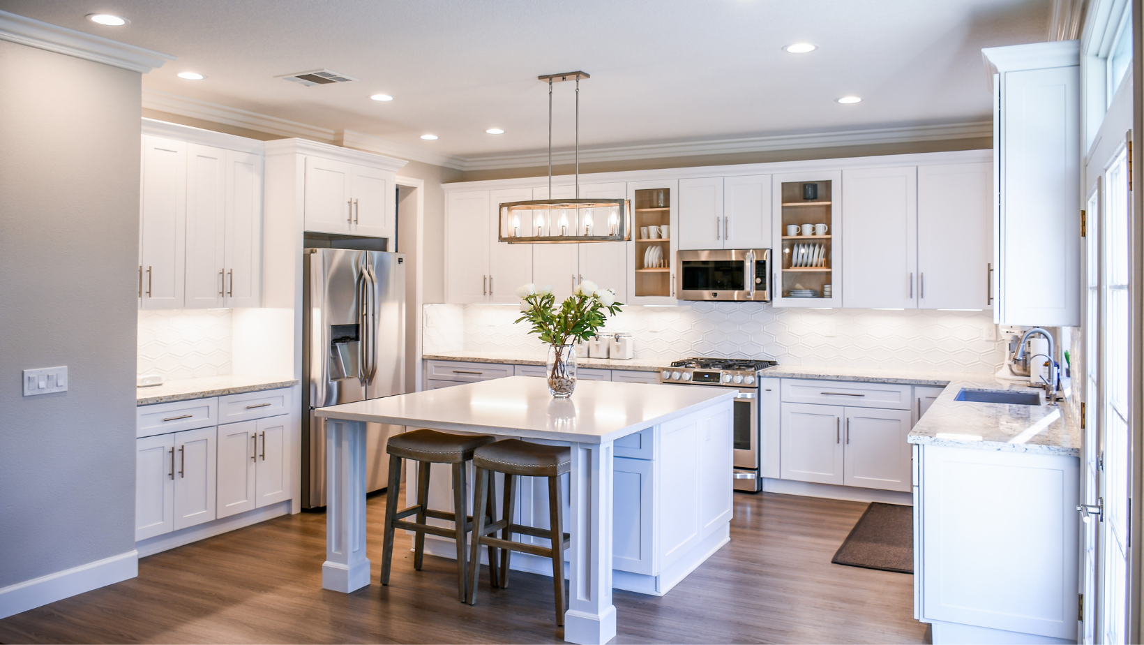 A kitchen with white cabinets , stainless steel appliances , and a large island.