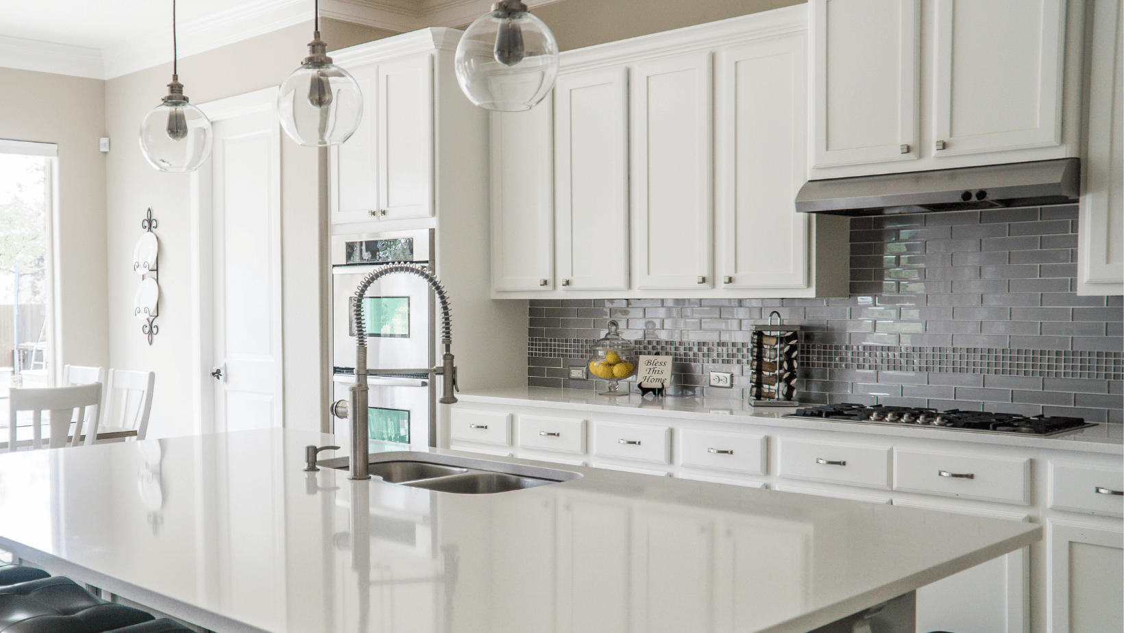 A kitchen with white cabinets , granite counter tops , stainless steel appliances and a large island.