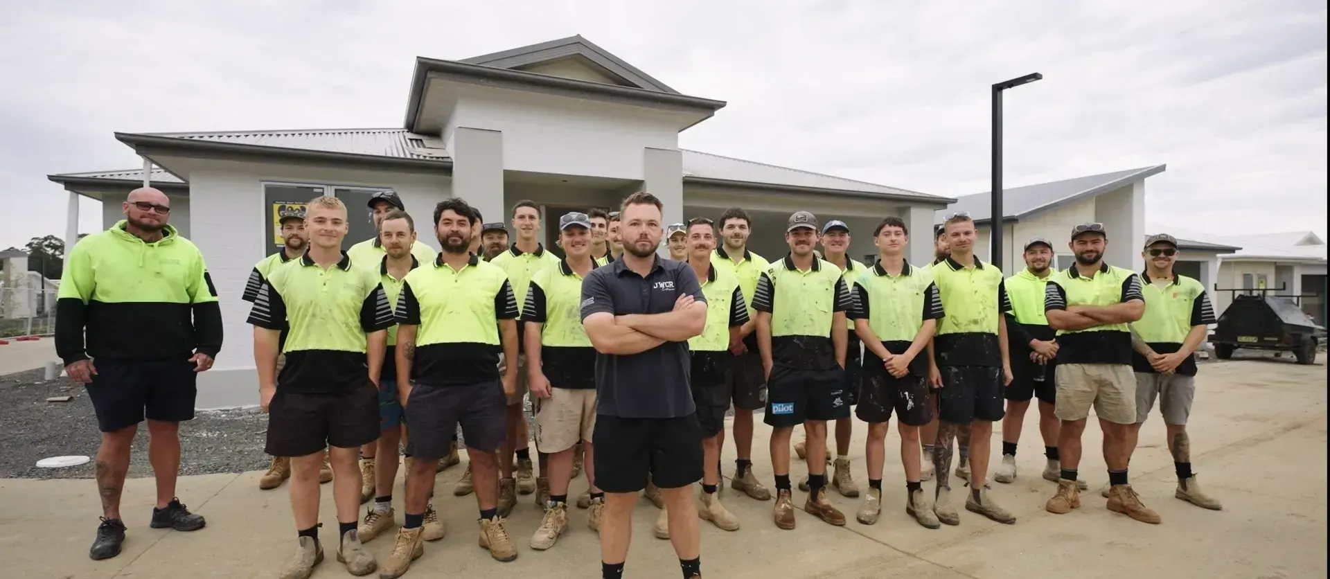 Construction workers are posing for a photo in front of a house. — J.White Carpentry & Renovations in Port Macquarie, NSW