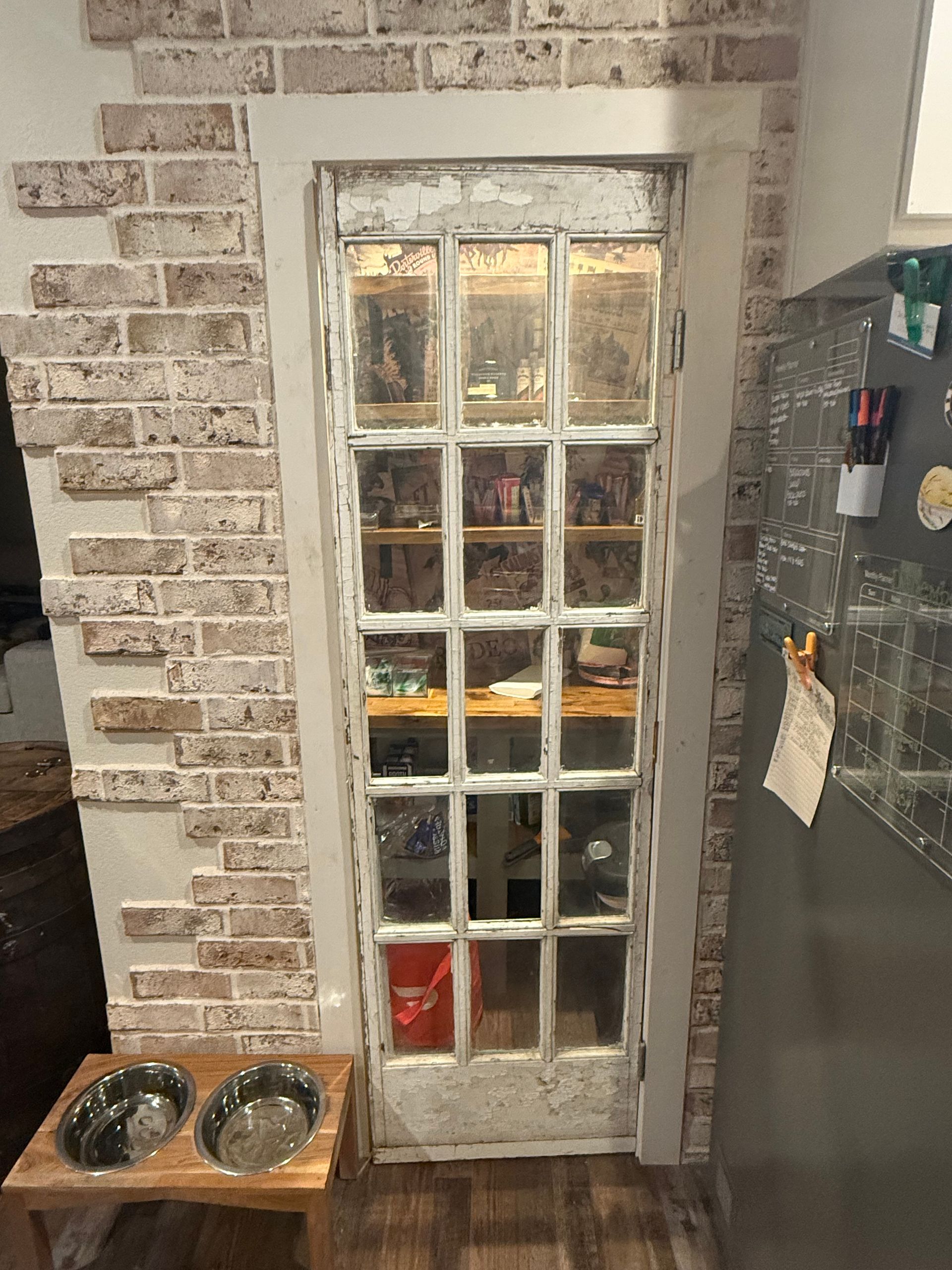 A kitchen with a brick wall and a glass door.