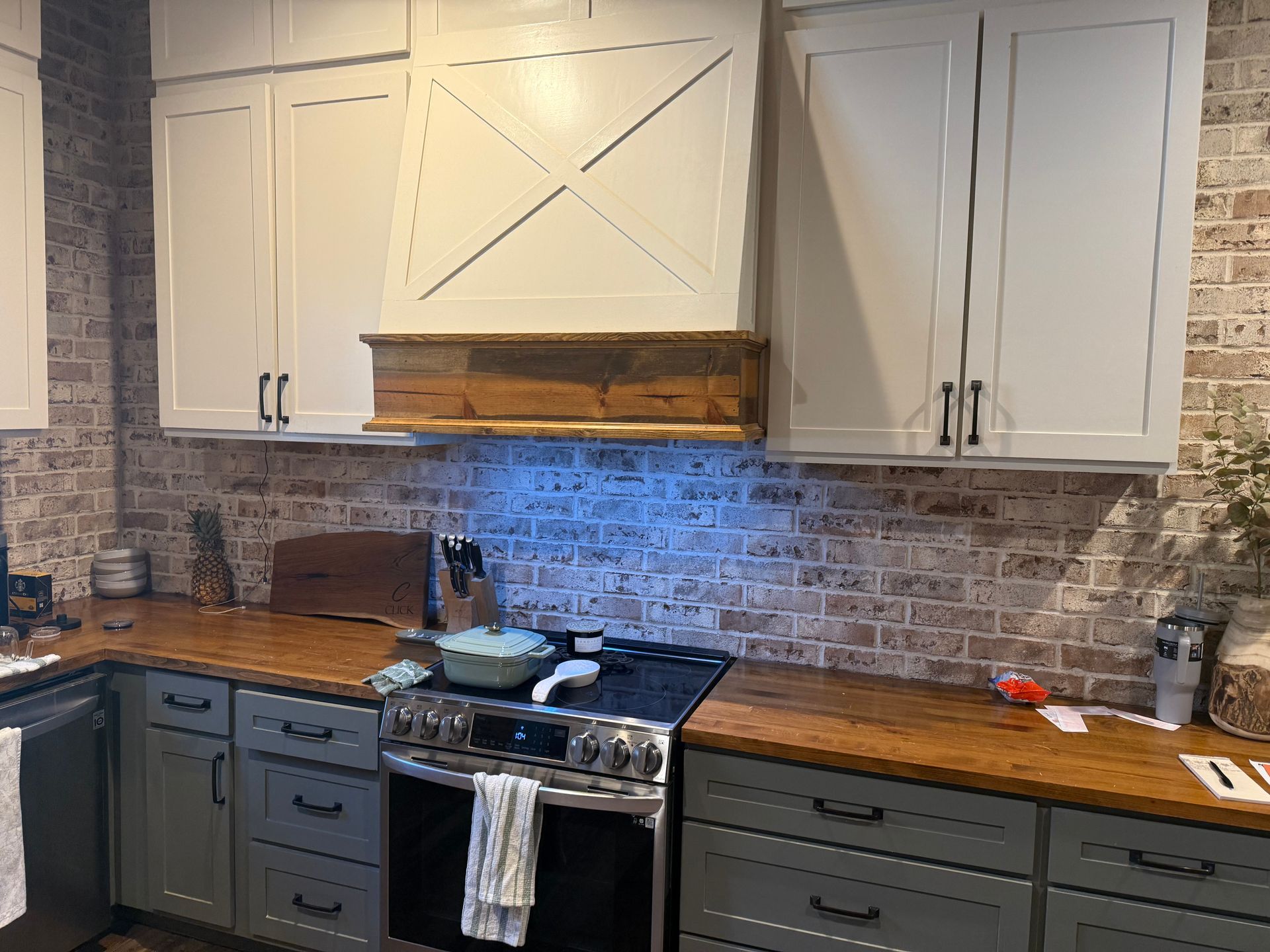 A kitchen with white cabinets , a stove , and a wooden counter top.