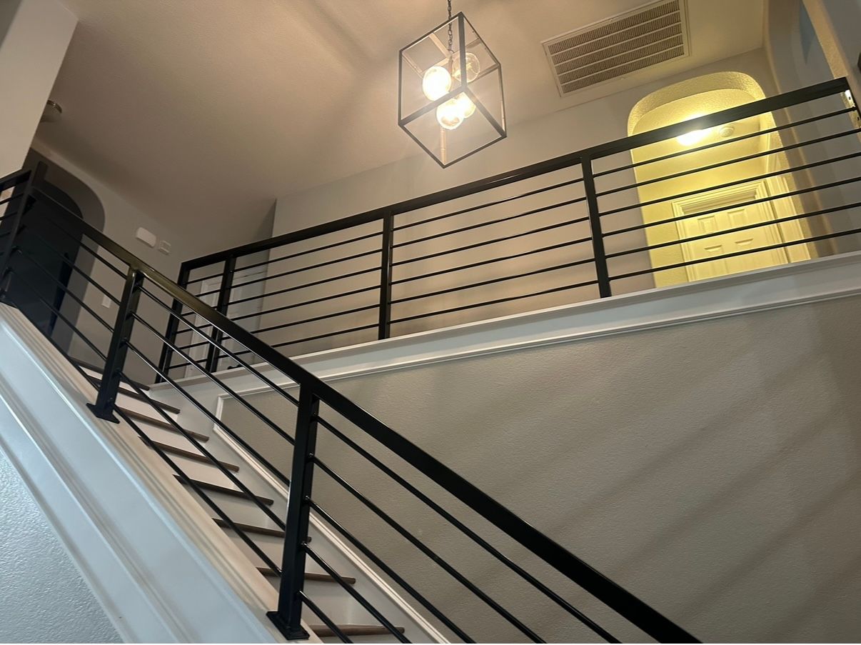 A staircase with a black railing and a light hanging from the ceiling