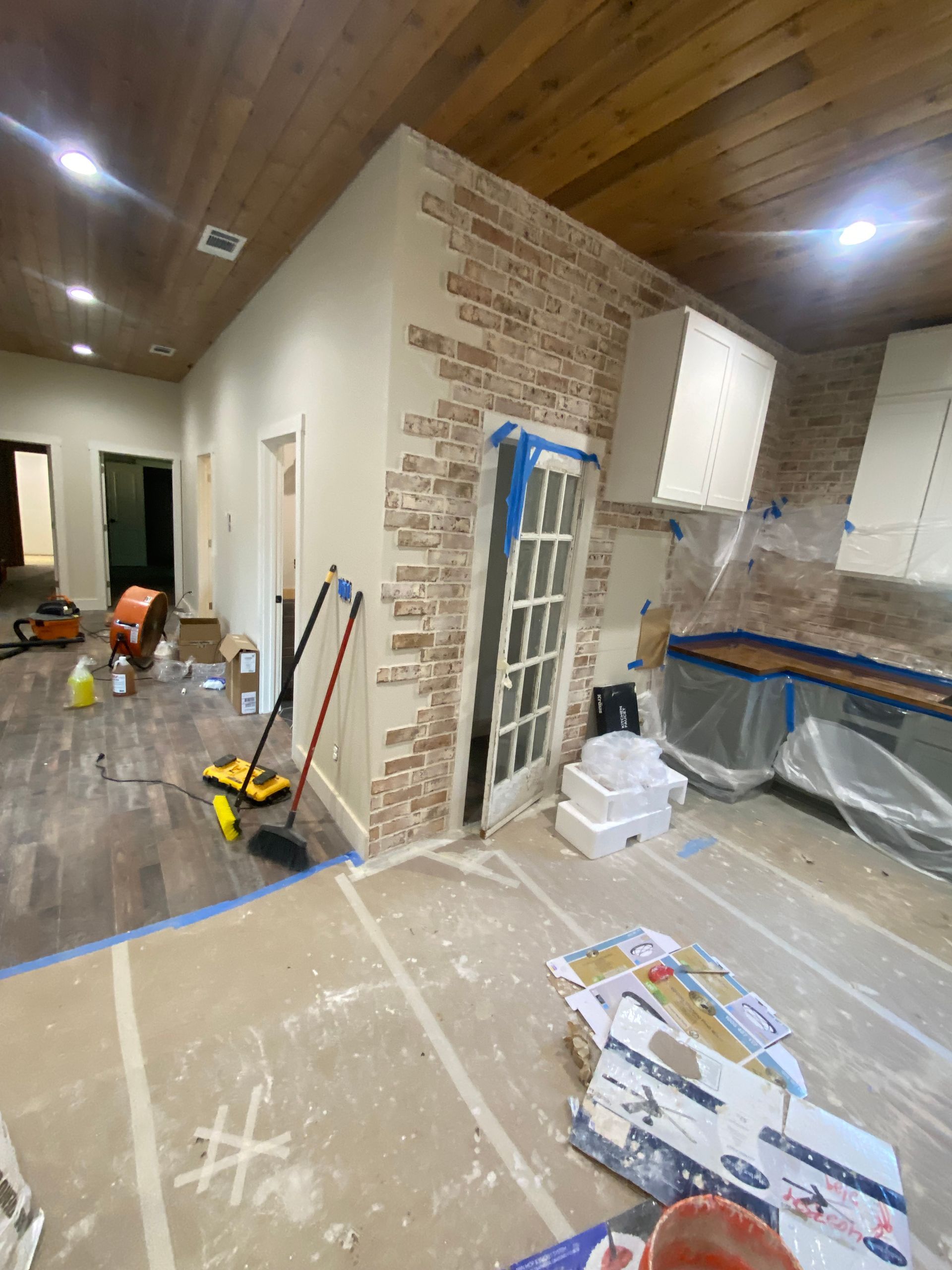 A room with a brick wall and a french door is being painted.