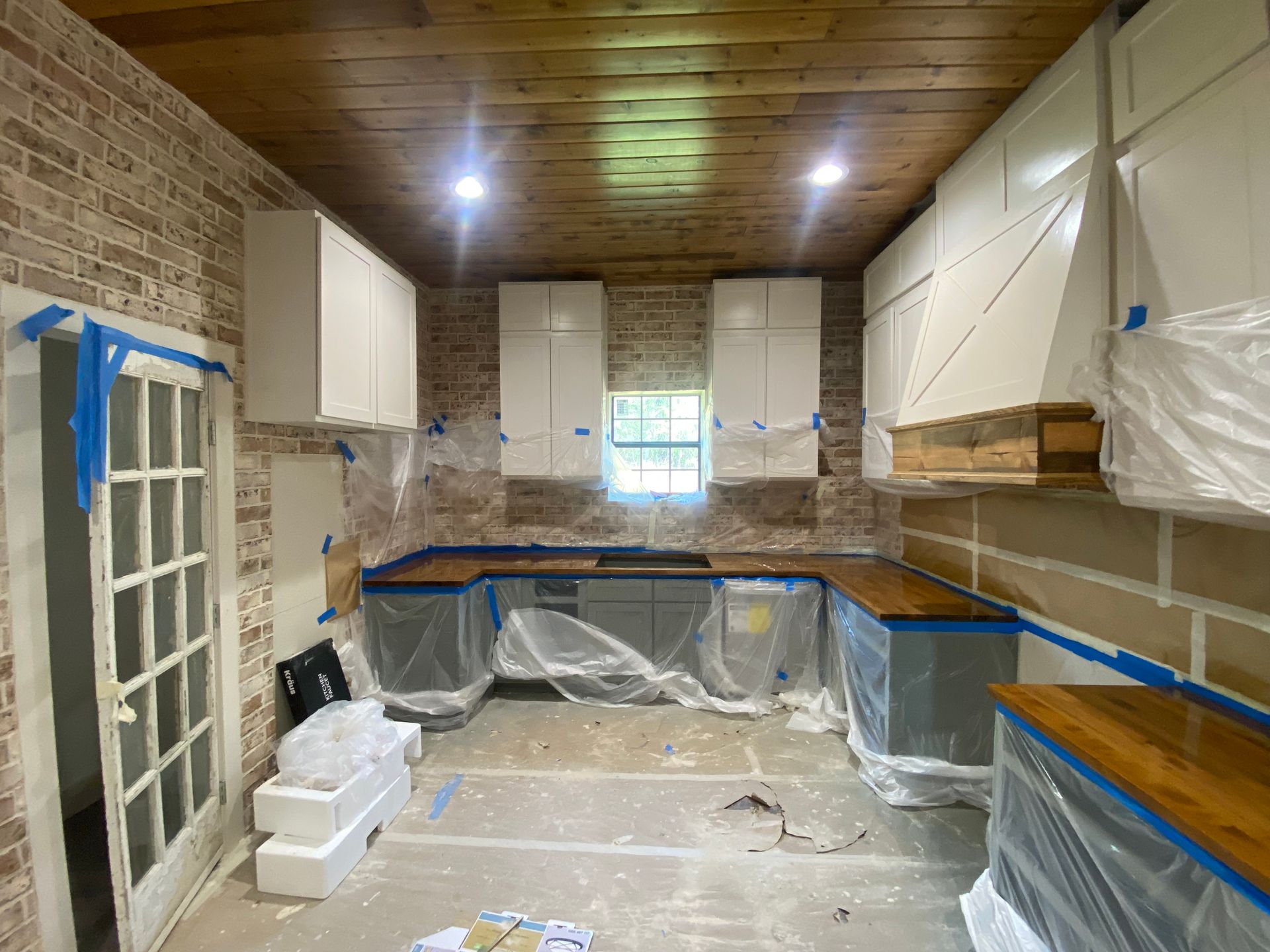 A kitchen with white cabinets and wooden counter tops is being painted.