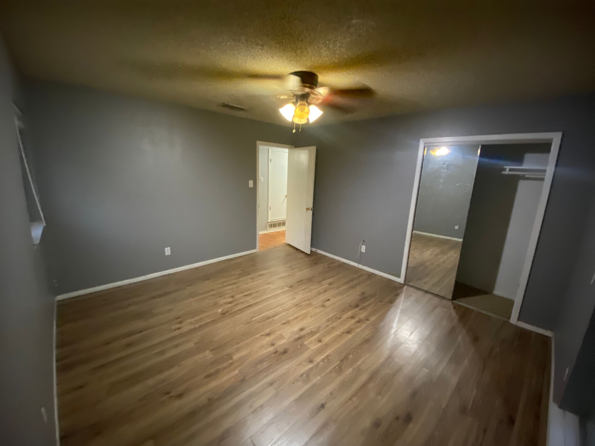 An empty room with hardwood floors and a ceiling fan.