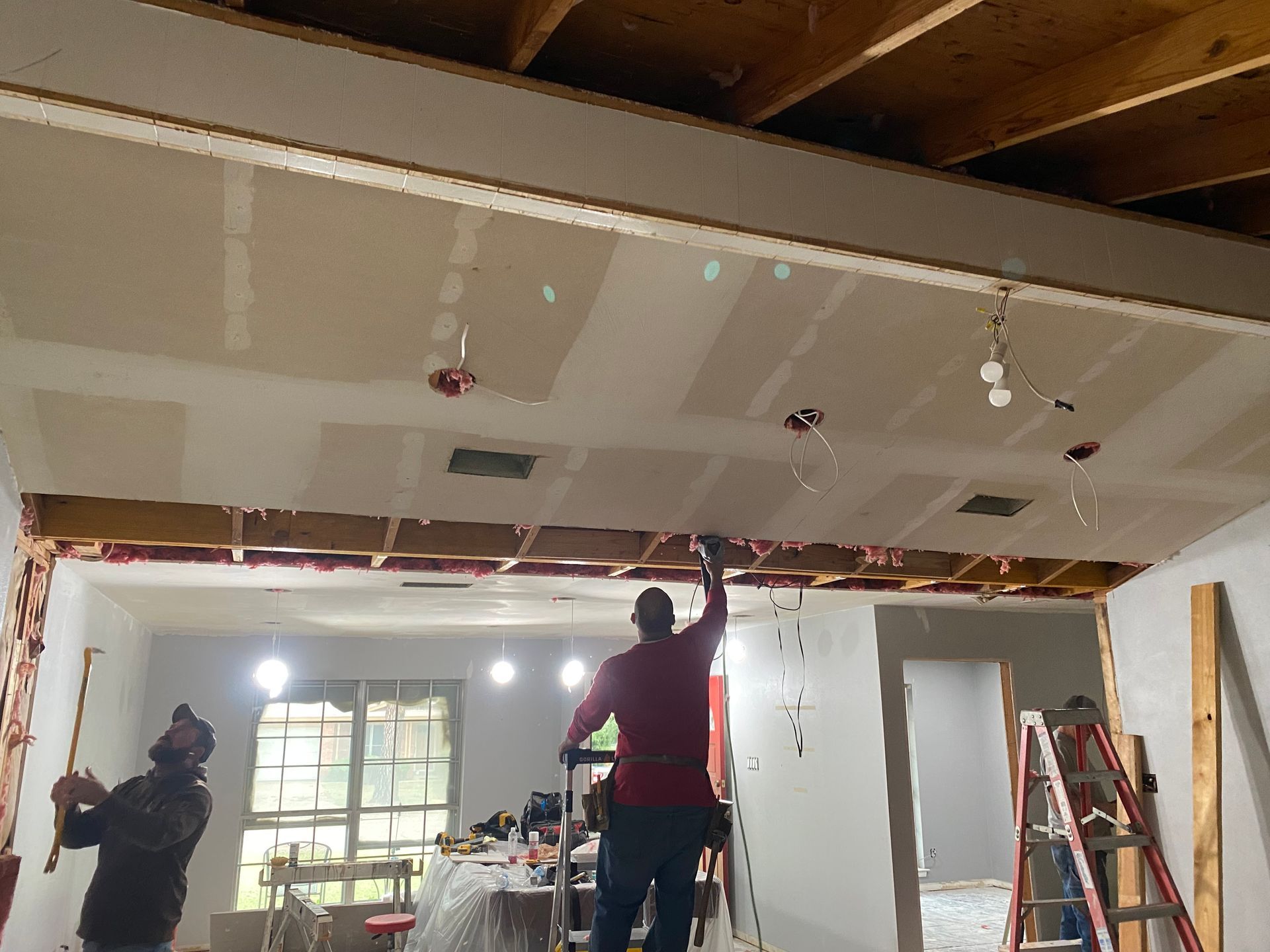 A man is working on the ceiling of a house.