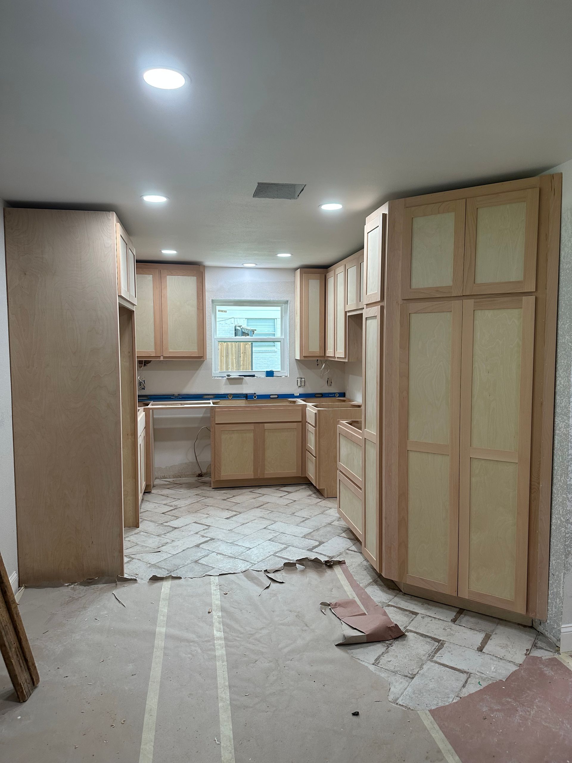 A kitchen under construction with wooden cabinets and a window.