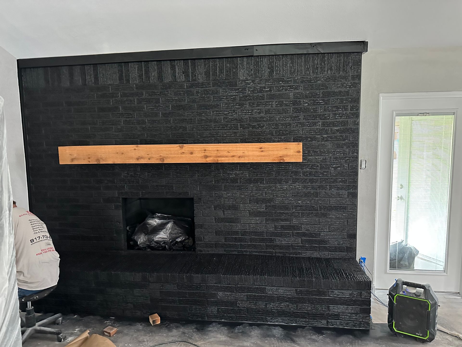 A black brick fireplace with a wooden mantle in a living room.
