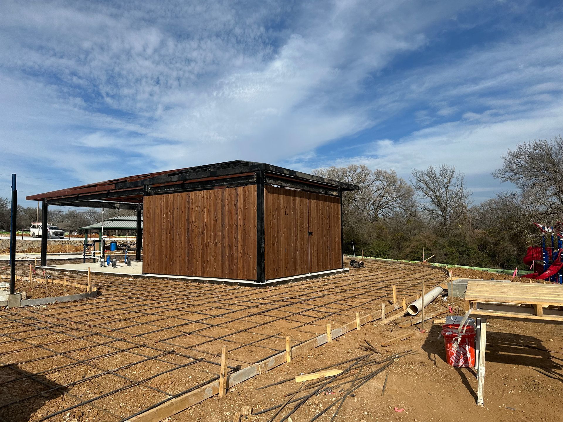 A wooden building is being built in a dirt field.