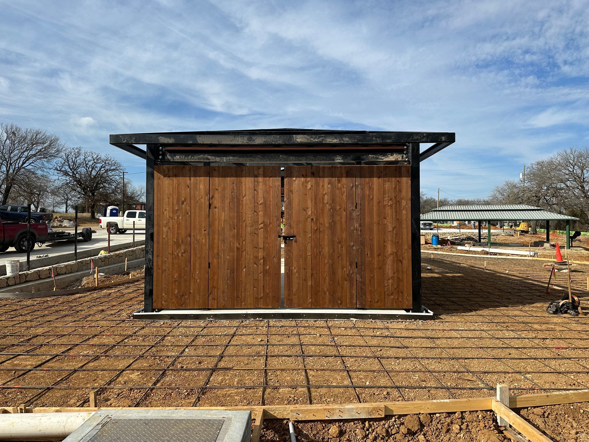 A wooden shed is sitting in the middle of a dirt field.