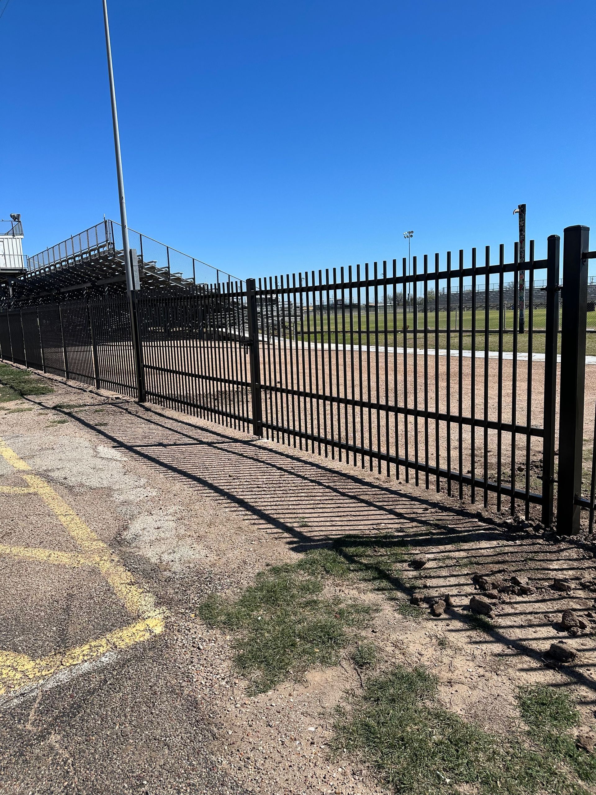 A black metal fence is surrounding a parking lot.