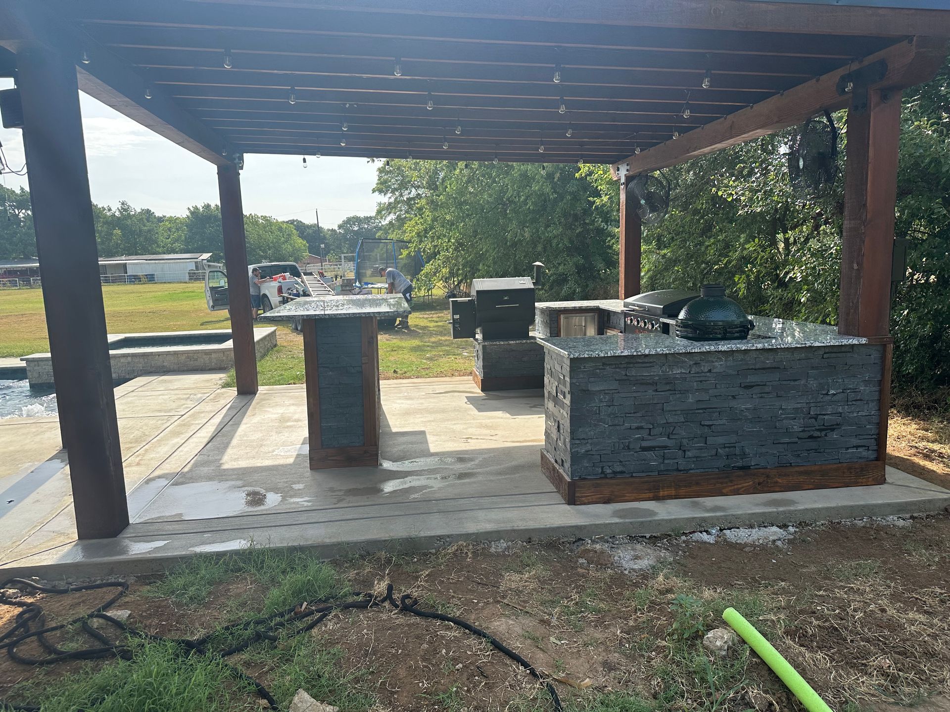 A patio area with a pergola and a kitchen in the backyard.