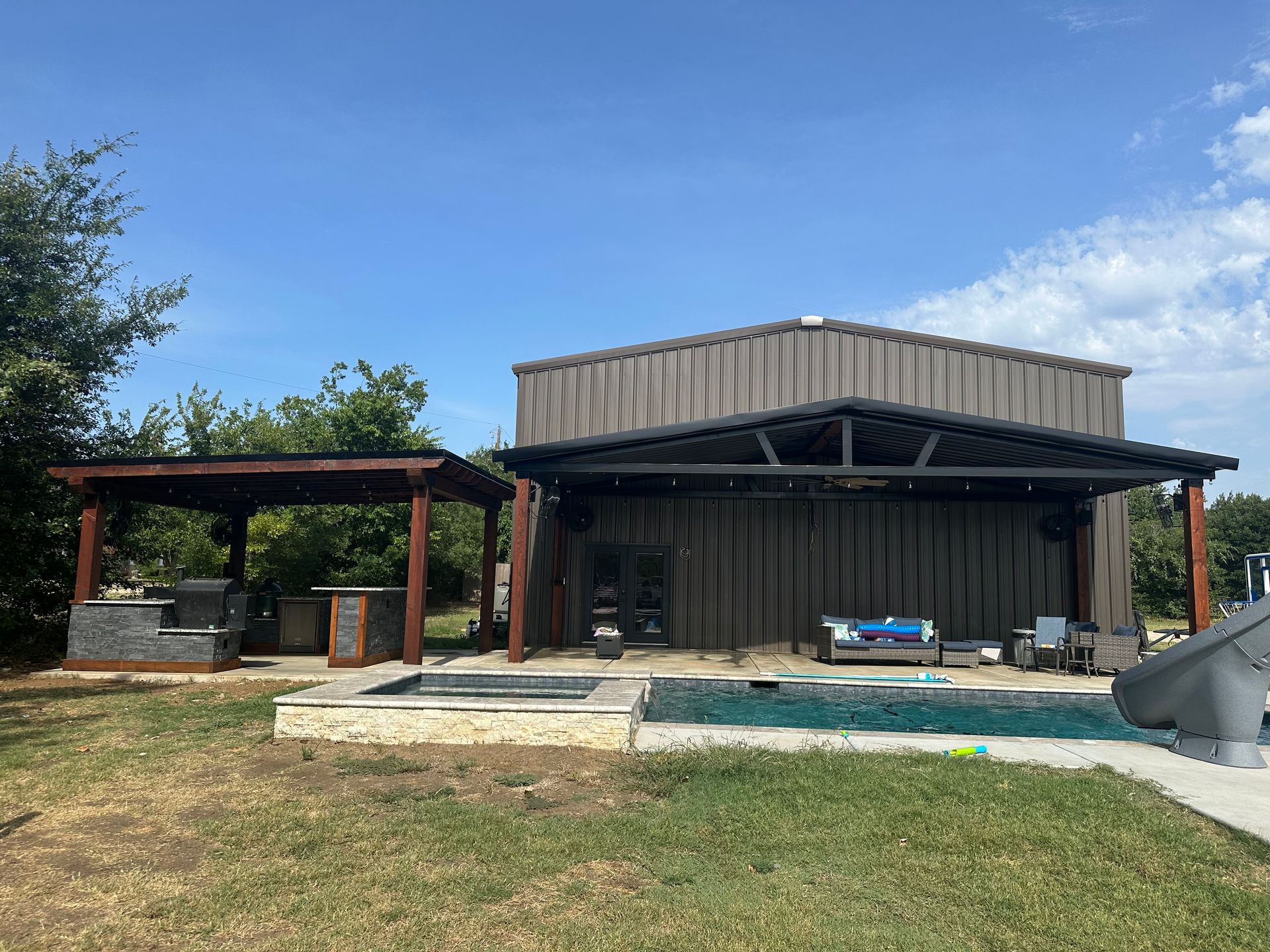 A large metal building with a swimming pool in front of it.
