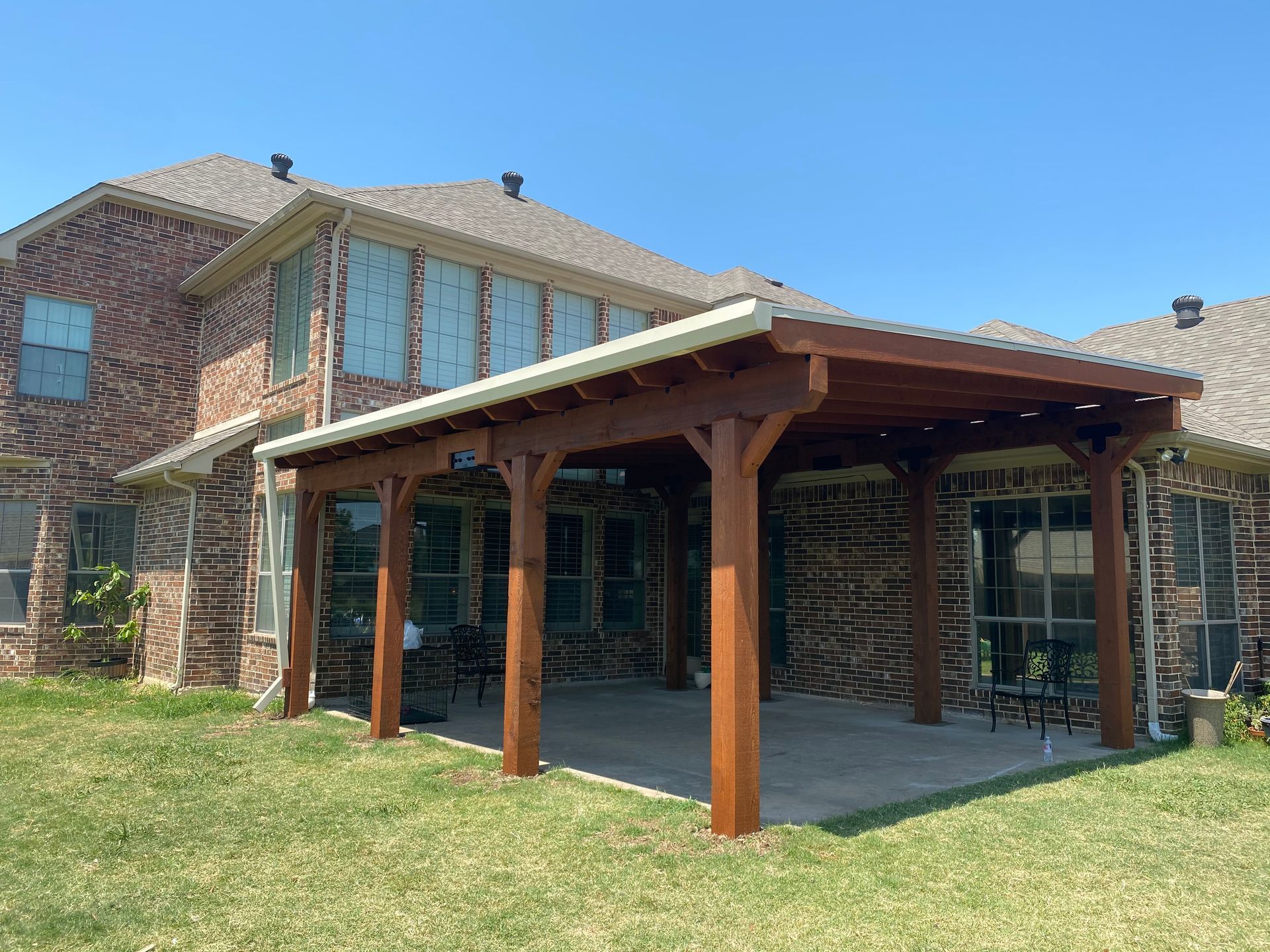 A large brick house with a wooden covered patio in front of it.