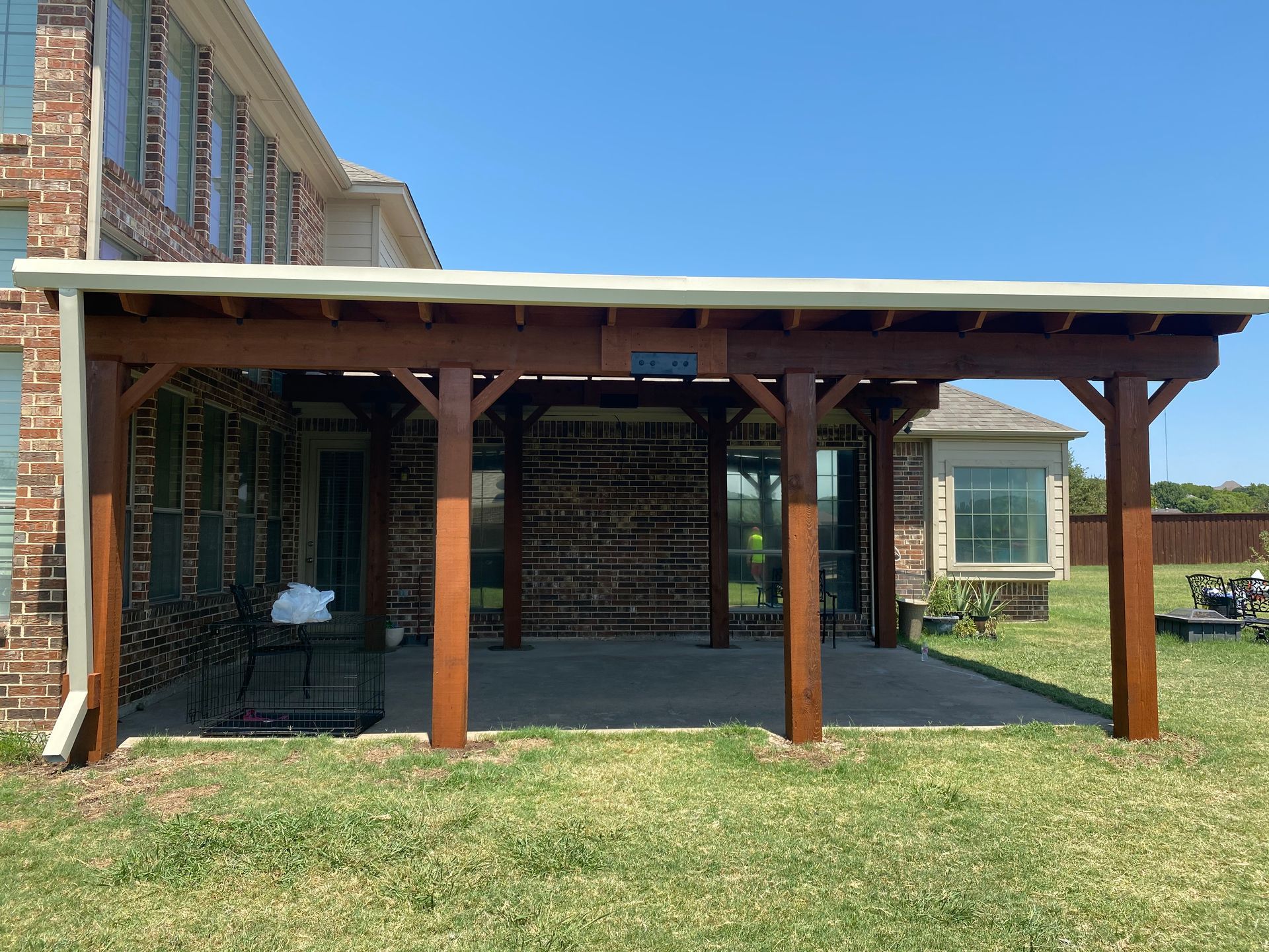 A wooden pergola is sitting in the backyard of a house.