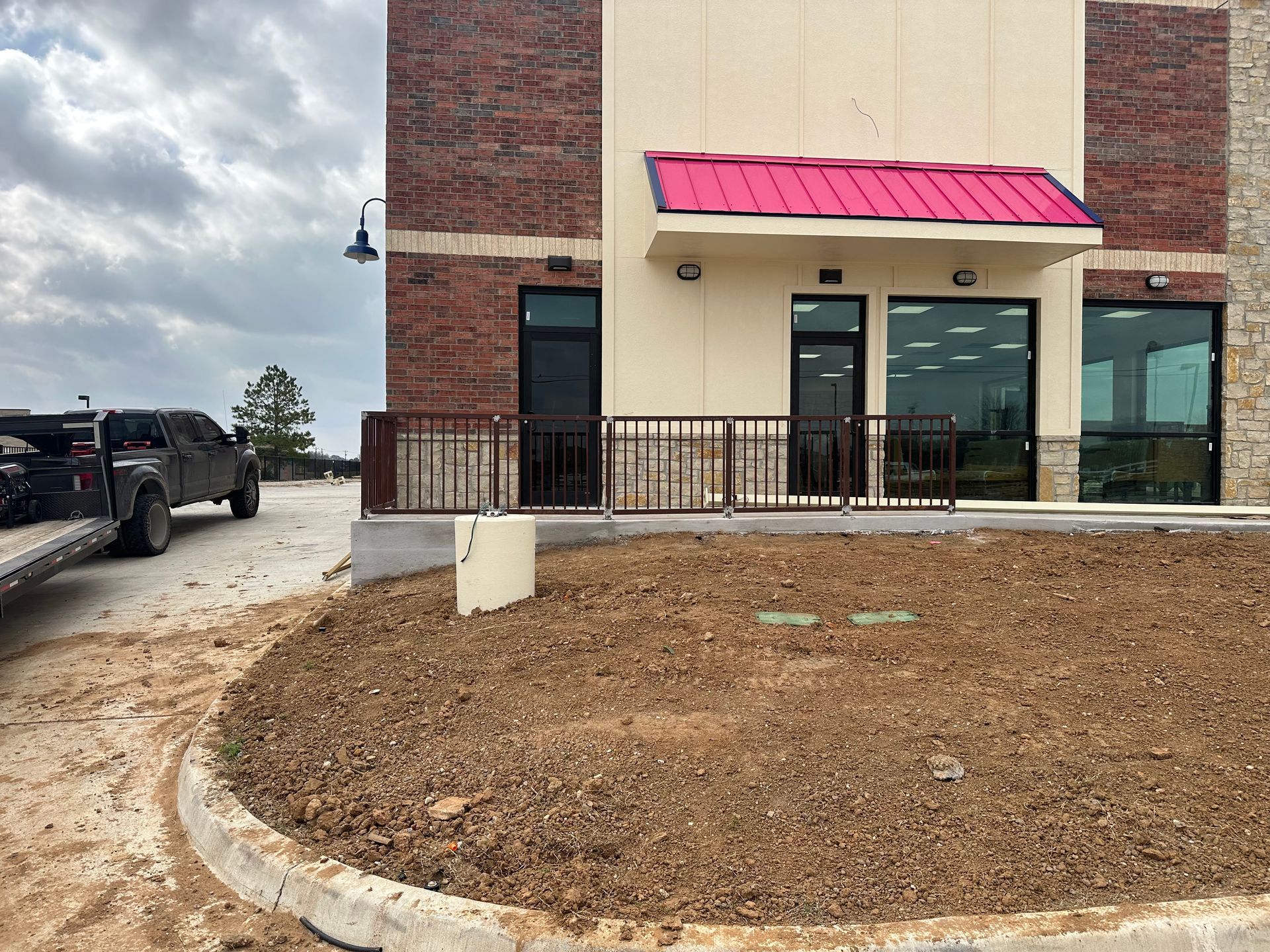 A truck is parked in front of a building with a red roof.