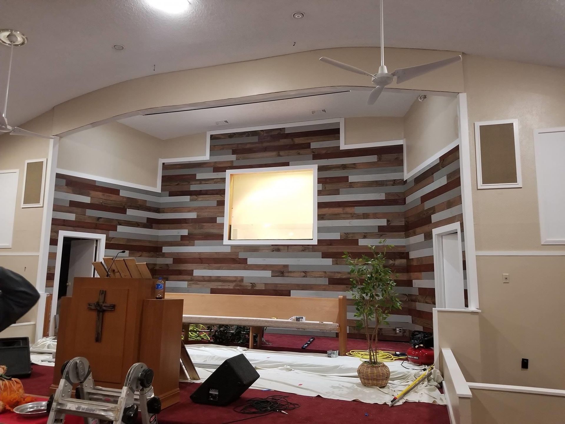 A church is being remodeled with a wooden wall and a podium.
