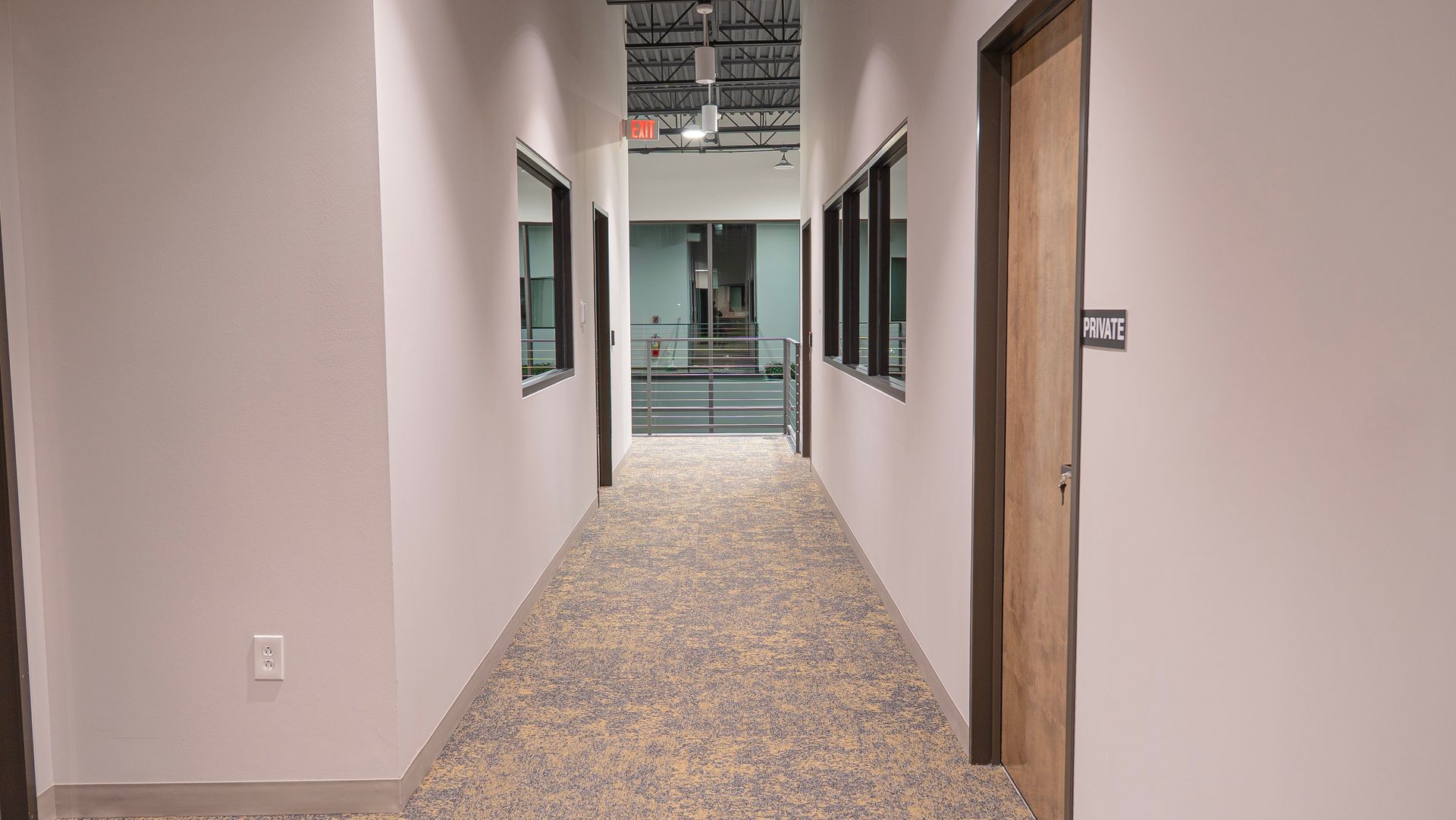 A long hallway in a building with a lot of windows and doors.